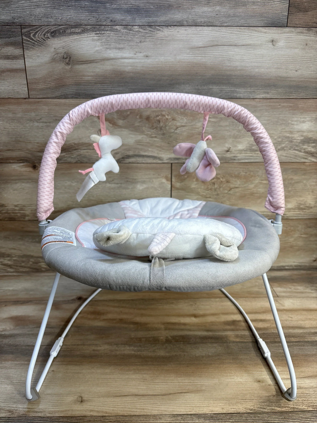 Pink and gray baby bouncer with unicorn toys, perfect for newborns and infants.