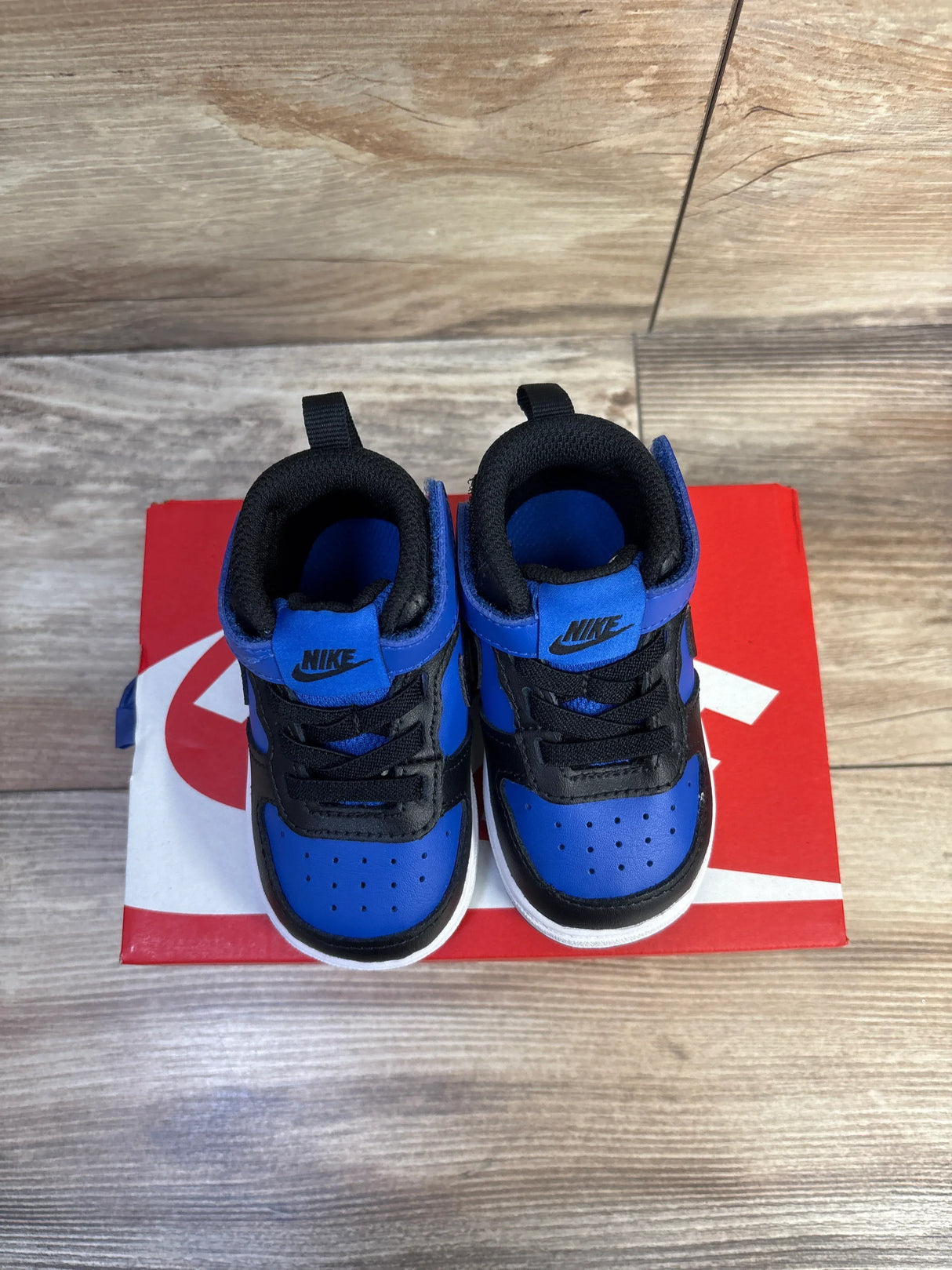 Top down view of toddler Nike Court Borough Mid 2 shoes in black and game royal showing velcro strap on red box