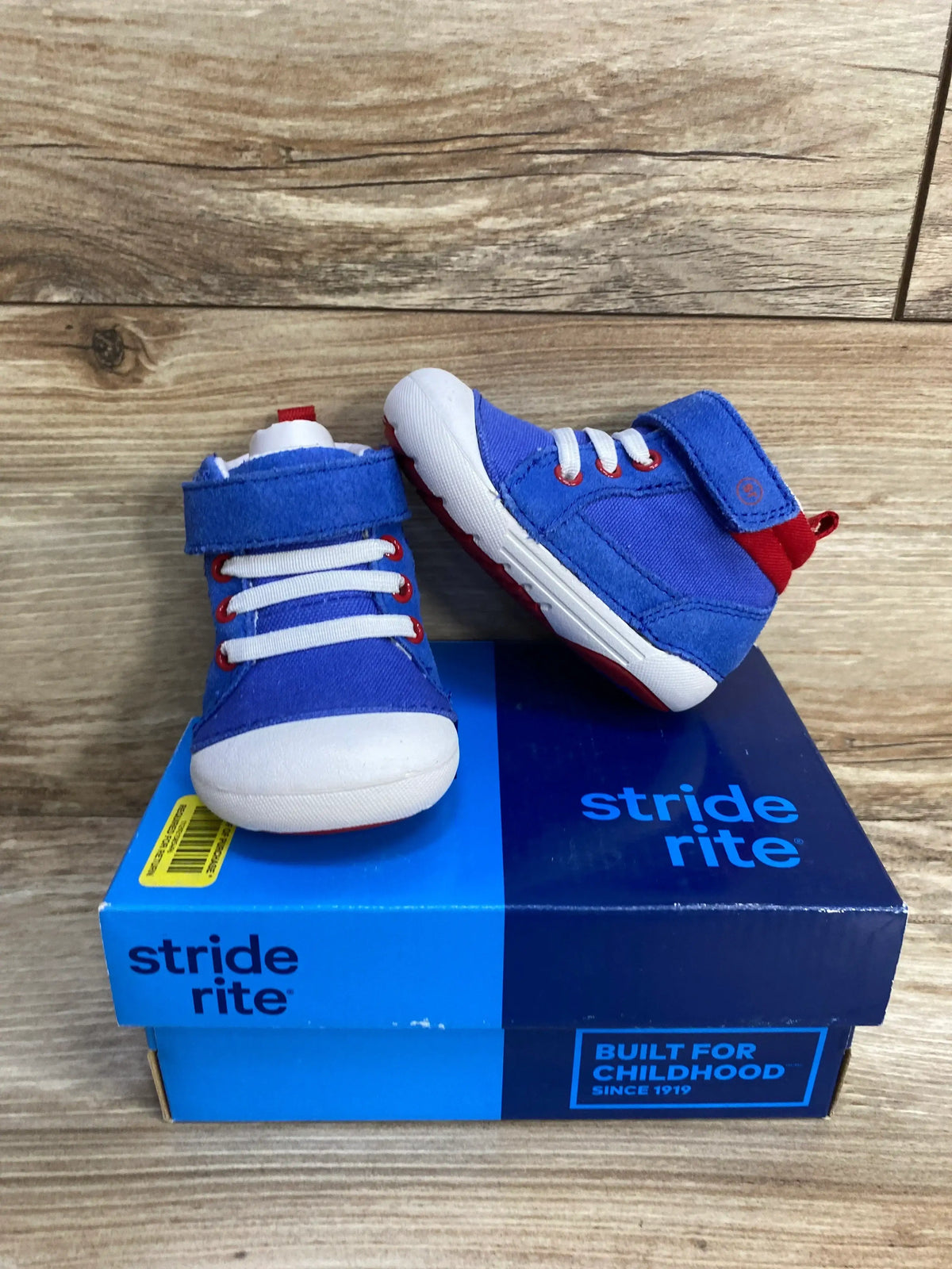 Front and side view of blue Stride Rite Danny sneakers with white rubber toe, elastic laces and velcro strap on blue shoebox