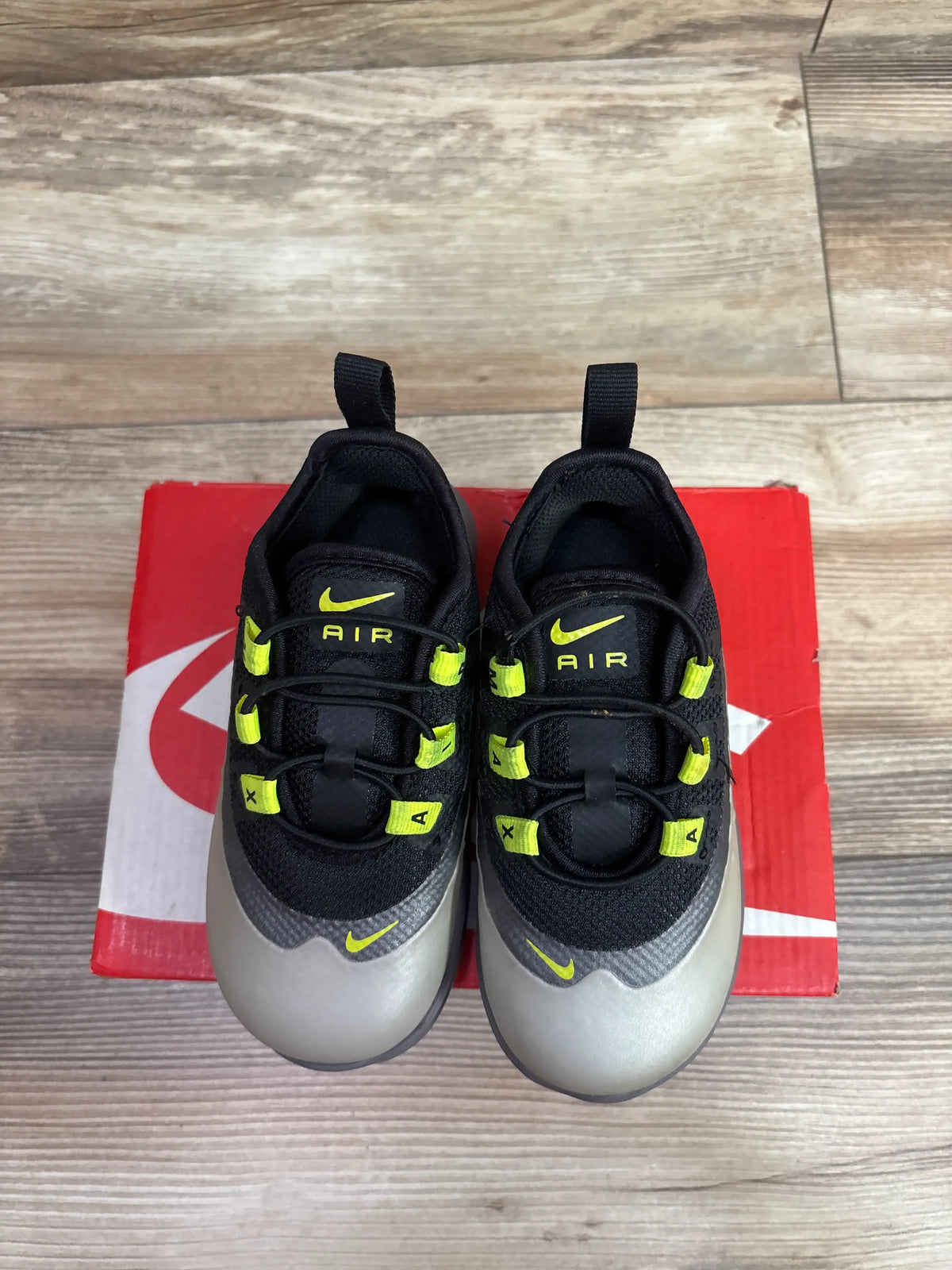 Top view of Nike Air Max Axis TD Black Volt sneakers for toddlers on a red shoebox.