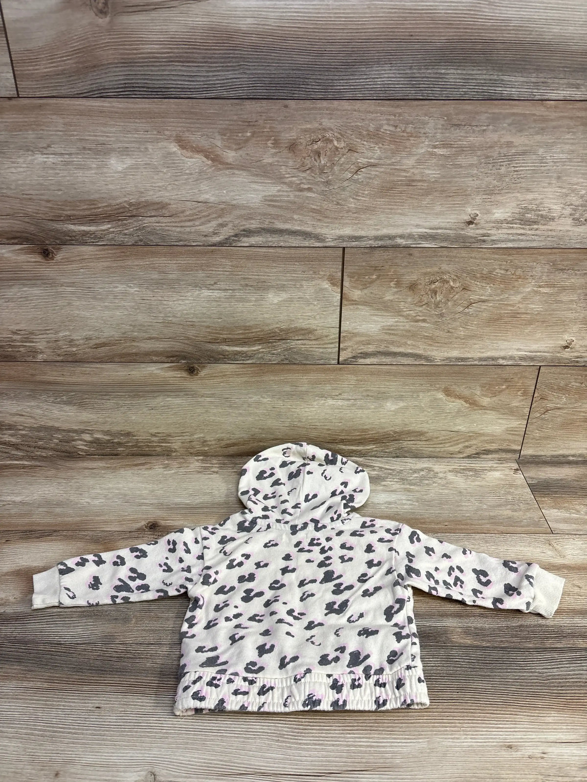 Top view of Grayson Mini off-white leopard print pull over sweater showcasing hood and ribbed cuffs on wood background