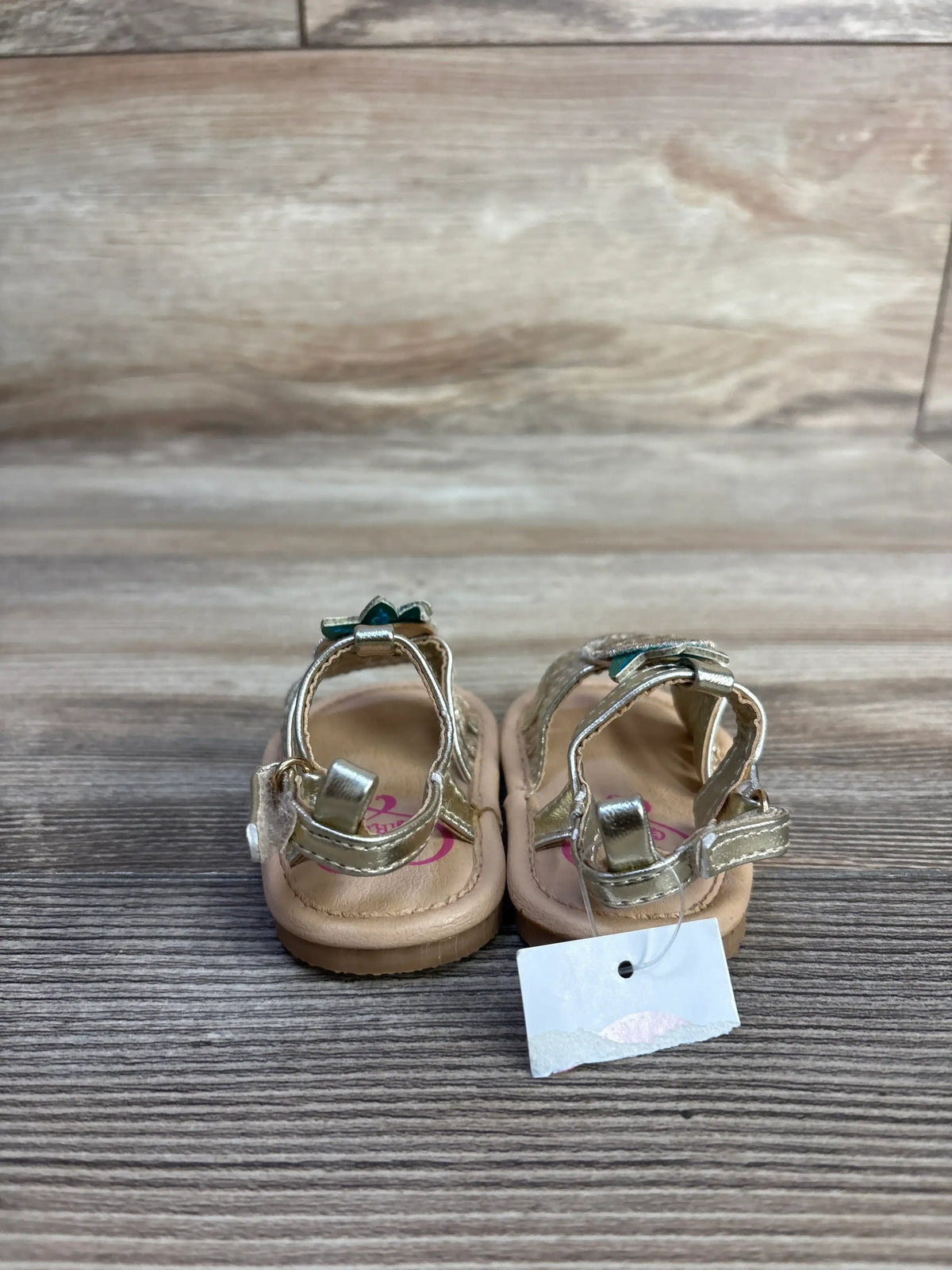 Rear view of NEW 143 girls pineapple sandals in size 1C showcasing metallic pineapple appliques and hook and loop ankle straps on a wood surface