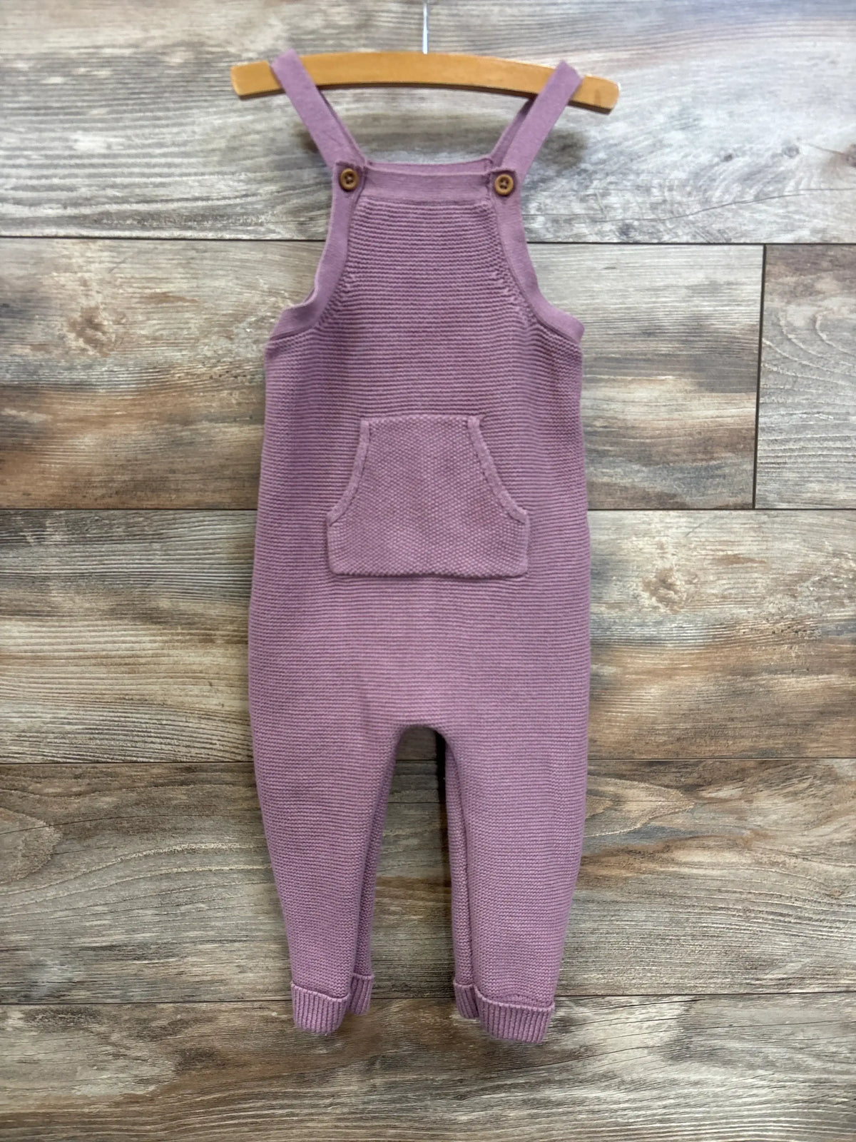 Front view of Little Planet knit overalls in mauve, size 18 months, showcasing knit texture and front pocket on wood