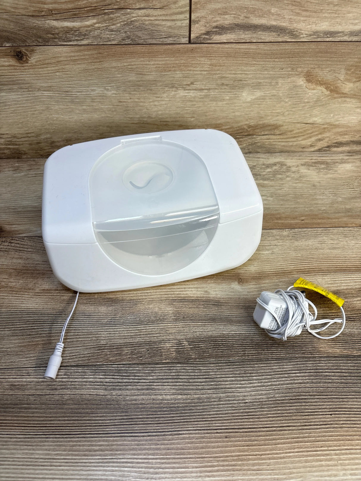 White baby wipe warmer with power cord on wooden surface