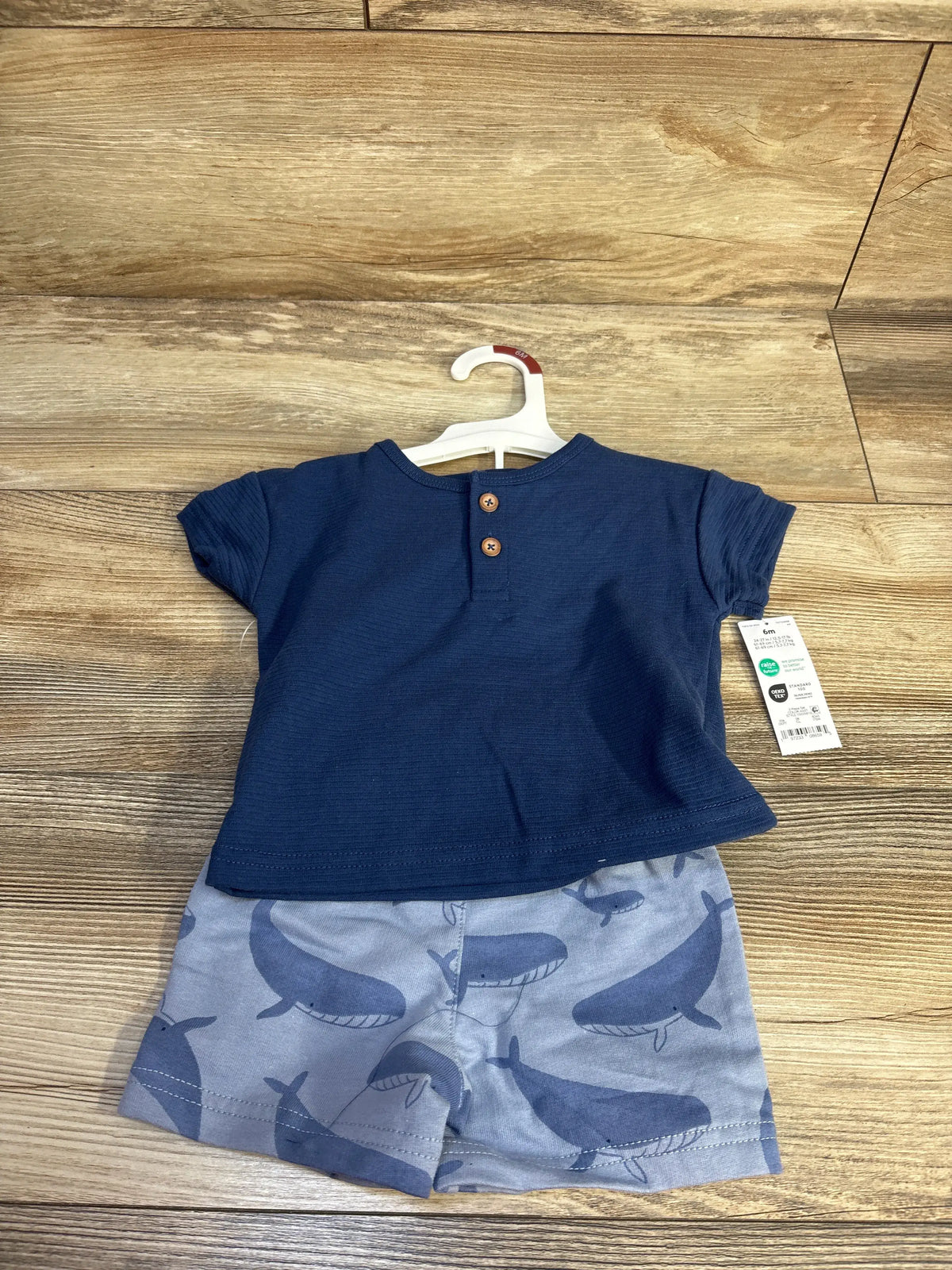 Front view of Just One You two-piece henley shirt and shorts set showcasing a blue two-button top and whale-print shorts on a wood floor