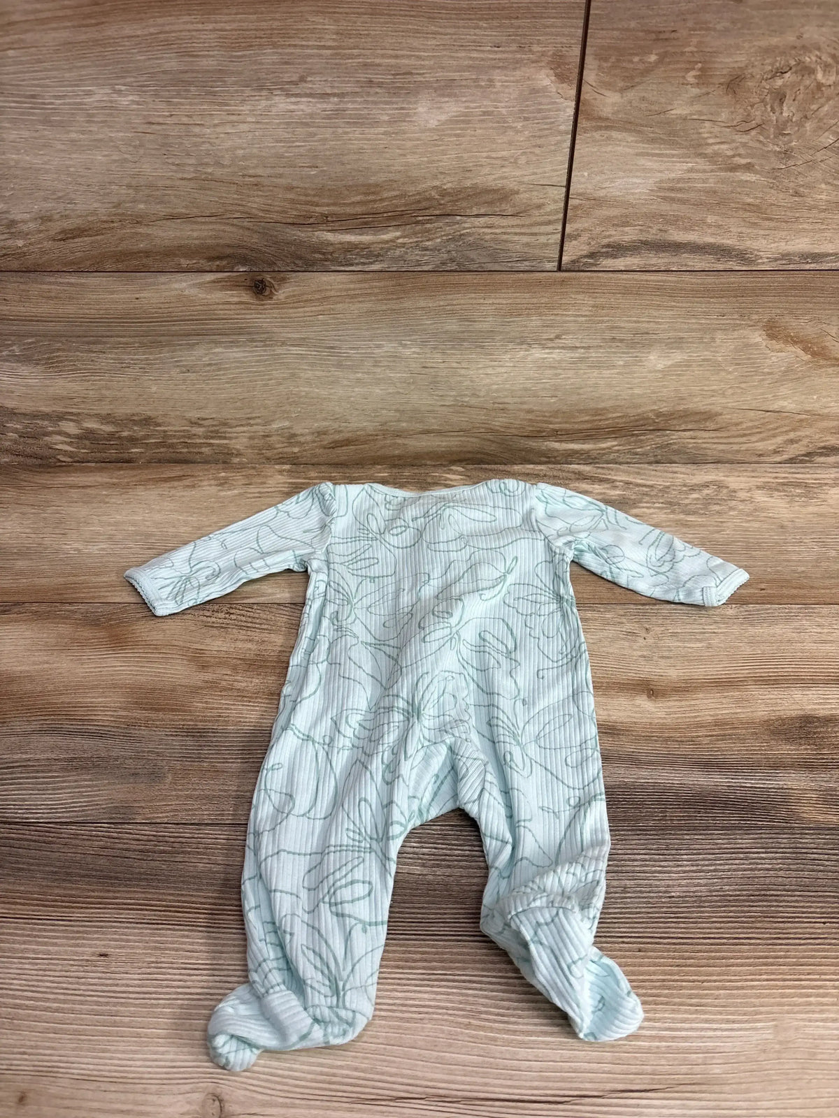 Flat lay of Carters Butterfly Ribbed Sleeper sz 3m showing teal butterfly outline print and footed long sleeve design on wood plank floor
