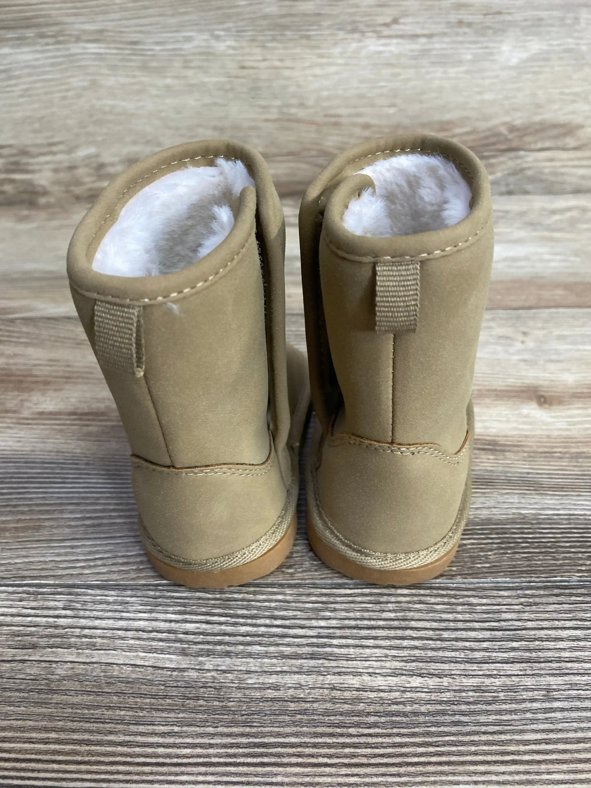 Tan suede toddler boots with faux fur lining, displayed on wood background