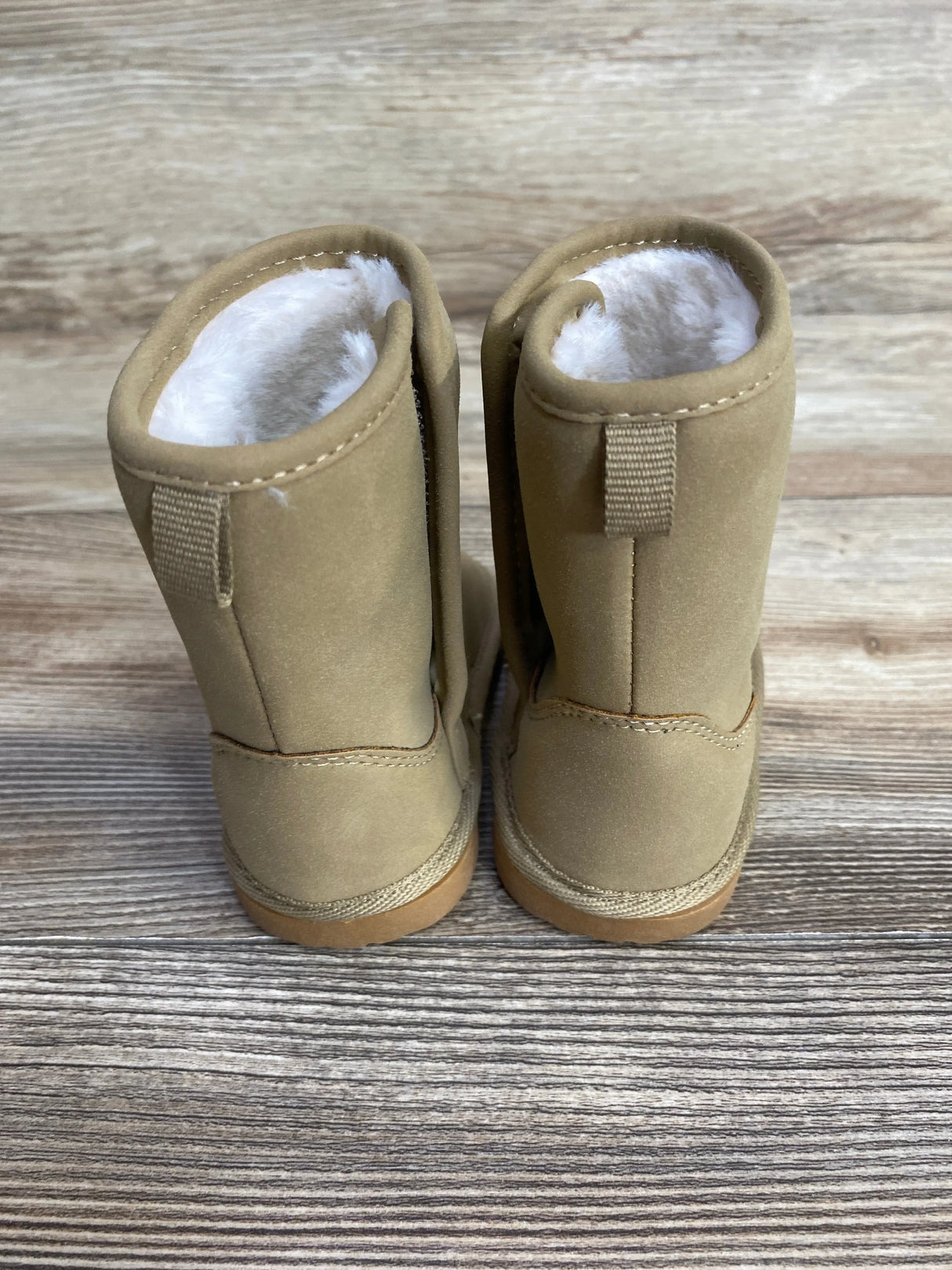 Tan suede toddler boots with faux fur lining, displayed on wood background