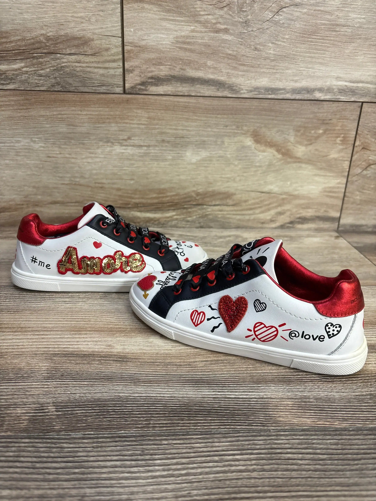 Side view of white Portofino DG Amore calfskin sneakers showcasing Amore lettering and heart graphics on a wood floor