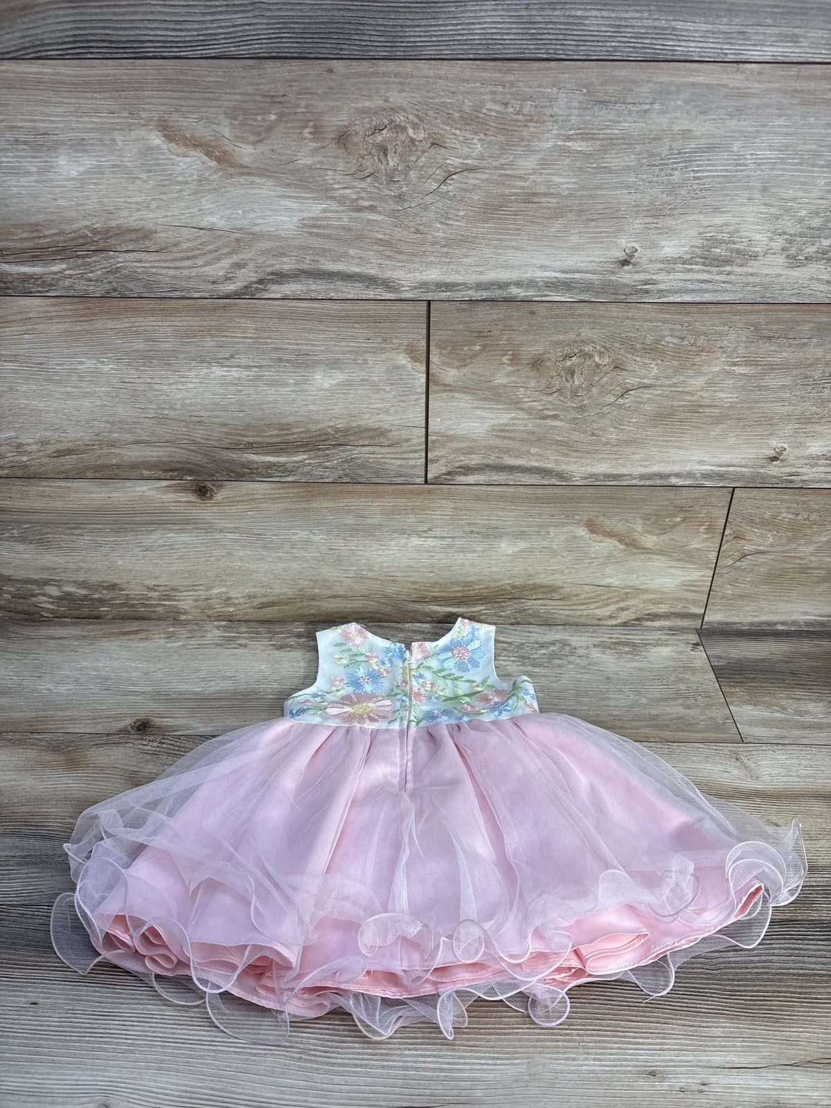 Back view of white Rare Editions tulle dress showcasing embroidered floral bodice and back zipper on wood-look flooring