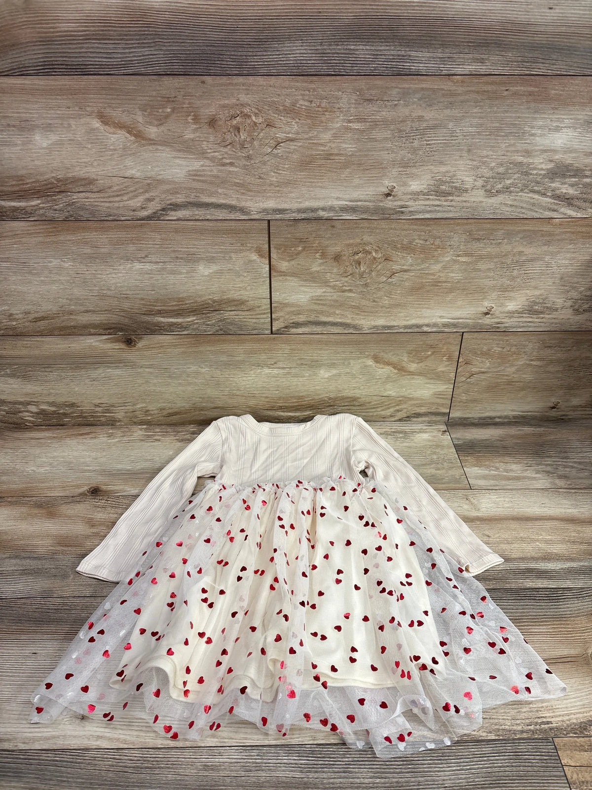 H&M cream long sleeve toddler dress with red heart print tulle skirt on a wood background