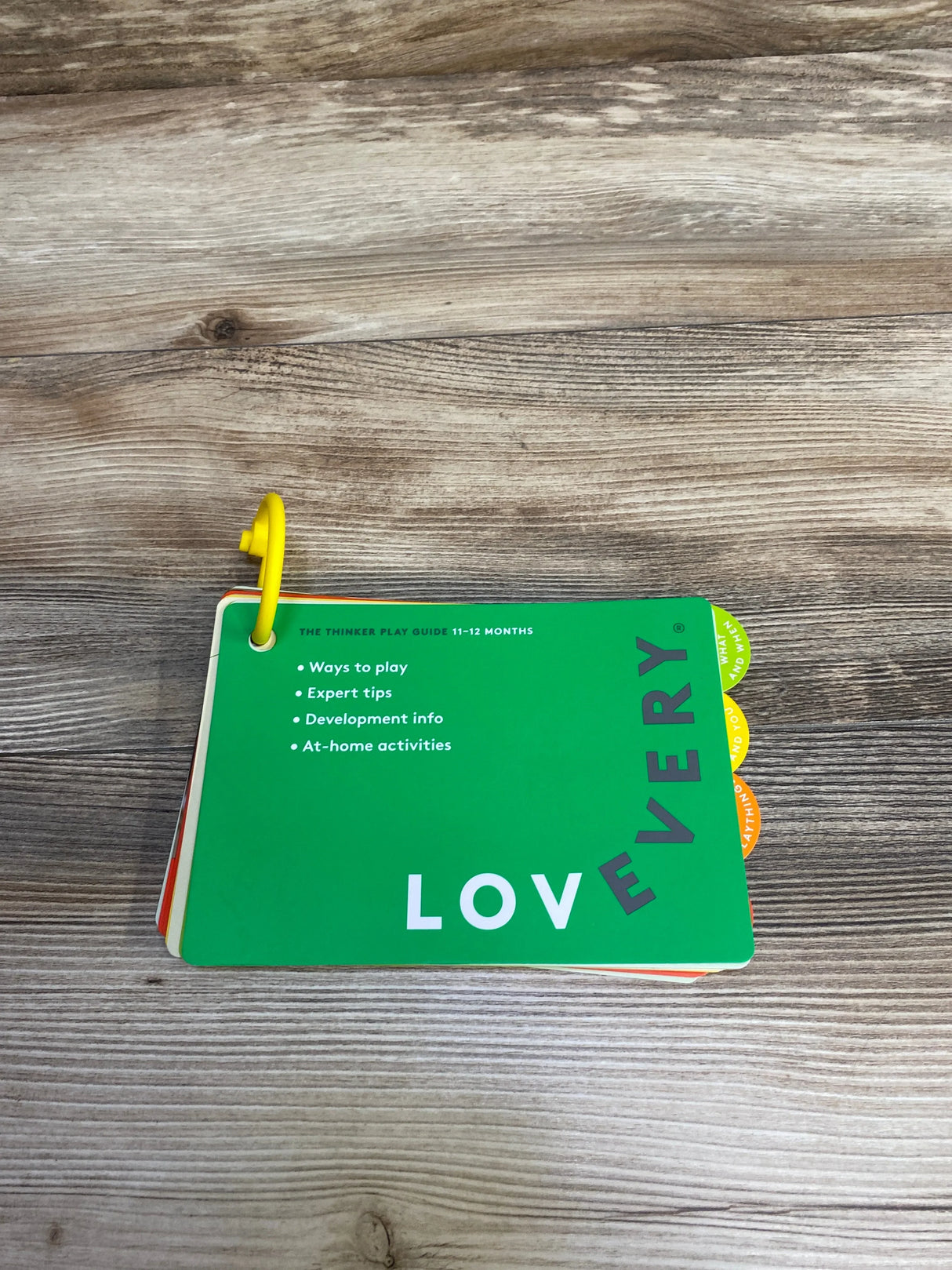 Lovevery 11-12 months play guide cards with tips and activities on wooden surface