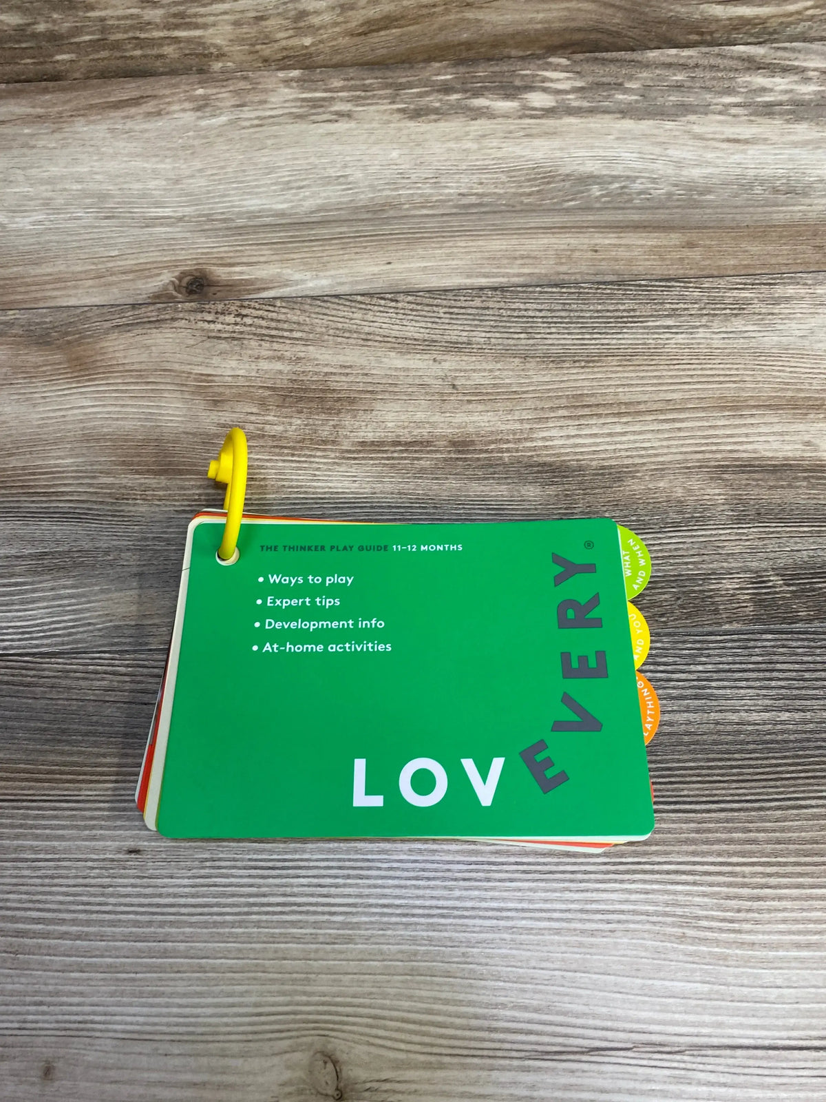 Lovevery 11-12 months play guide cards with tips and activities on wooden surface