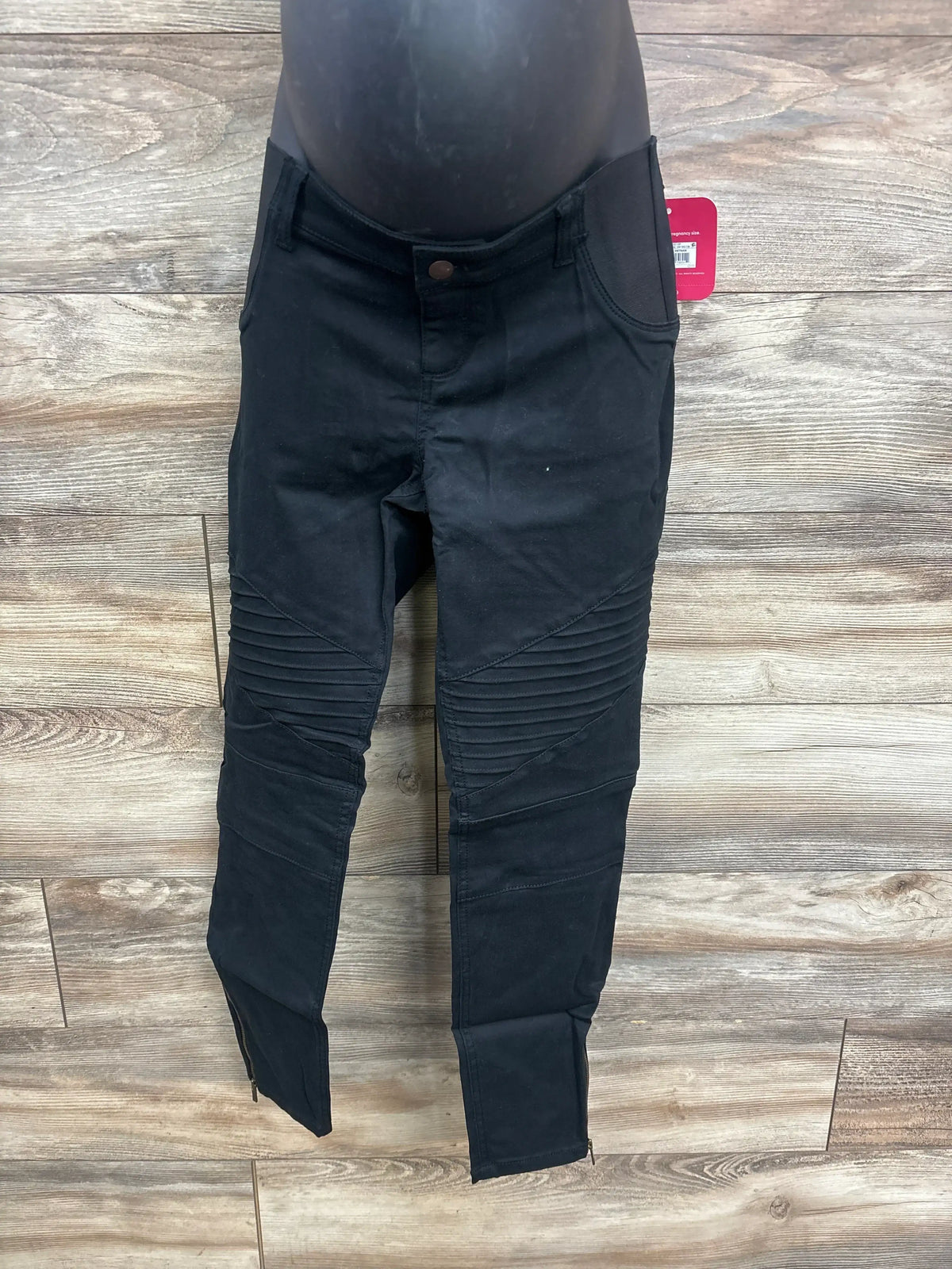 Front view of Isabel maternity utility jeggings in black showing ribbed knee panels, zip ankle hems and elastic belly panel on wood floor background