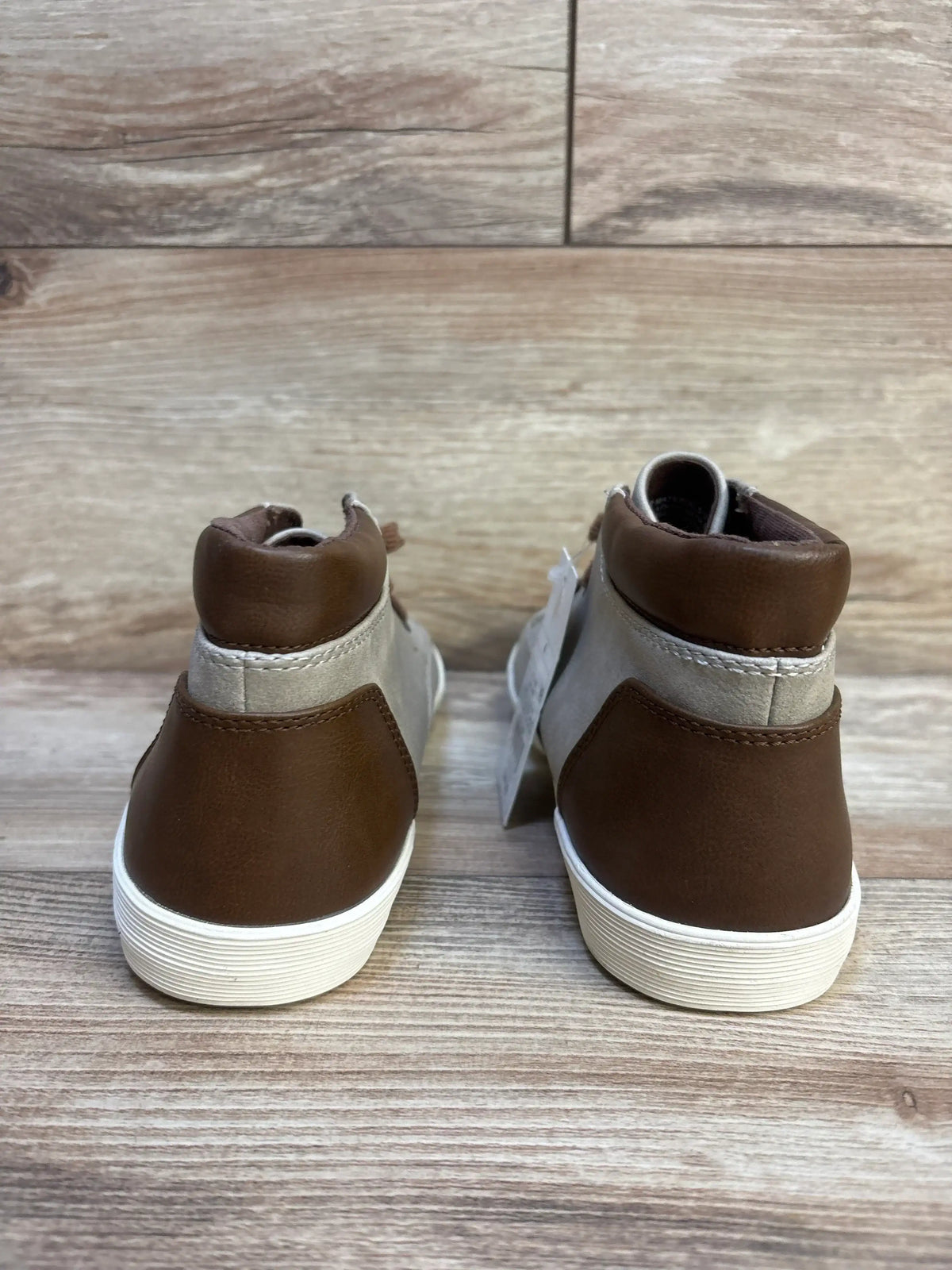 Brown and gray kids' high-top sneakers with white soles, viewed from the back on wood floor
