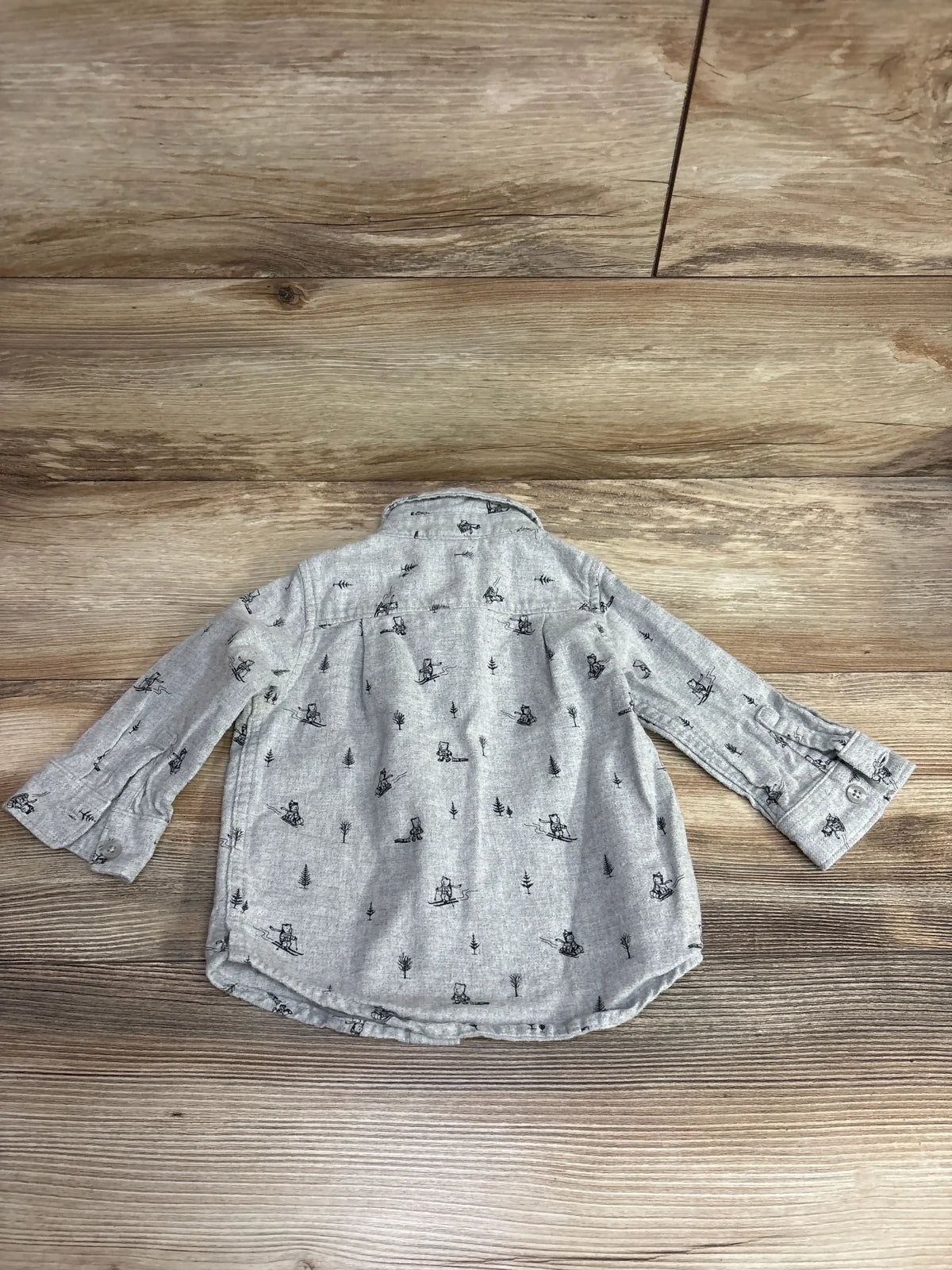 Gray long-sleeve toddler shirt with black skiing bear and tree print on wooden background