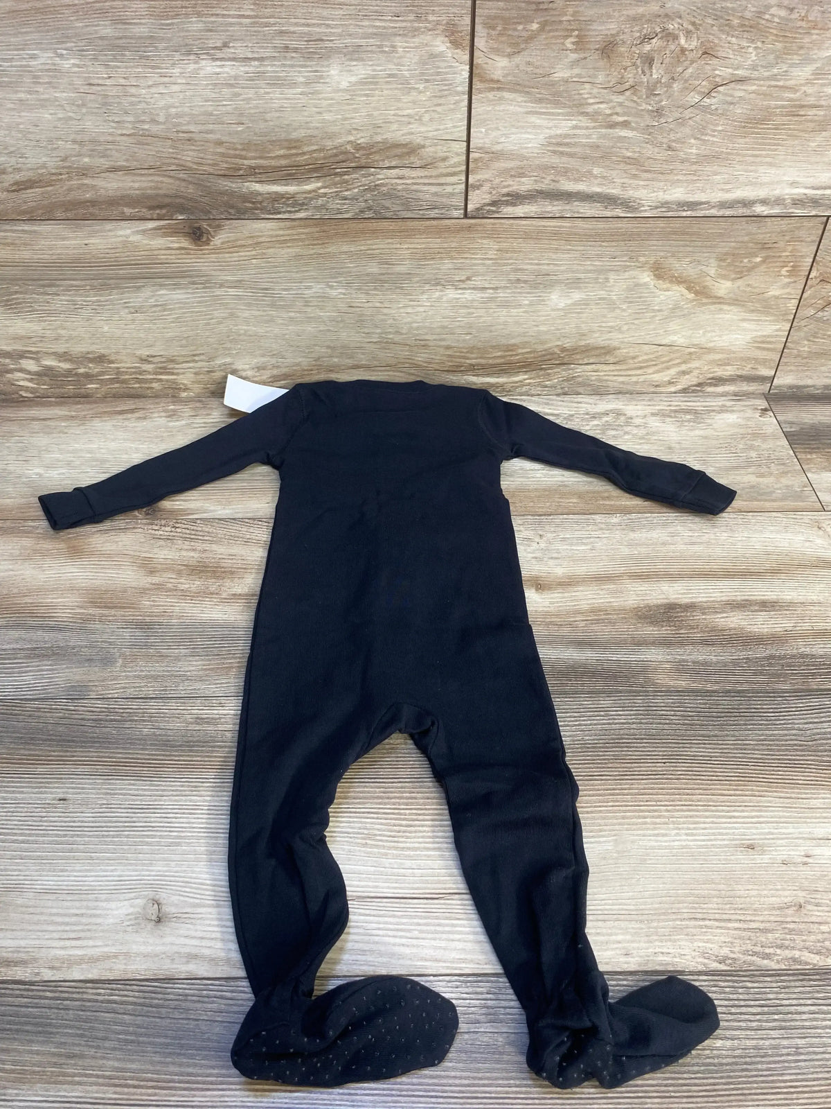 Black long sleeve baby footed sleeper laid flat on wood floor