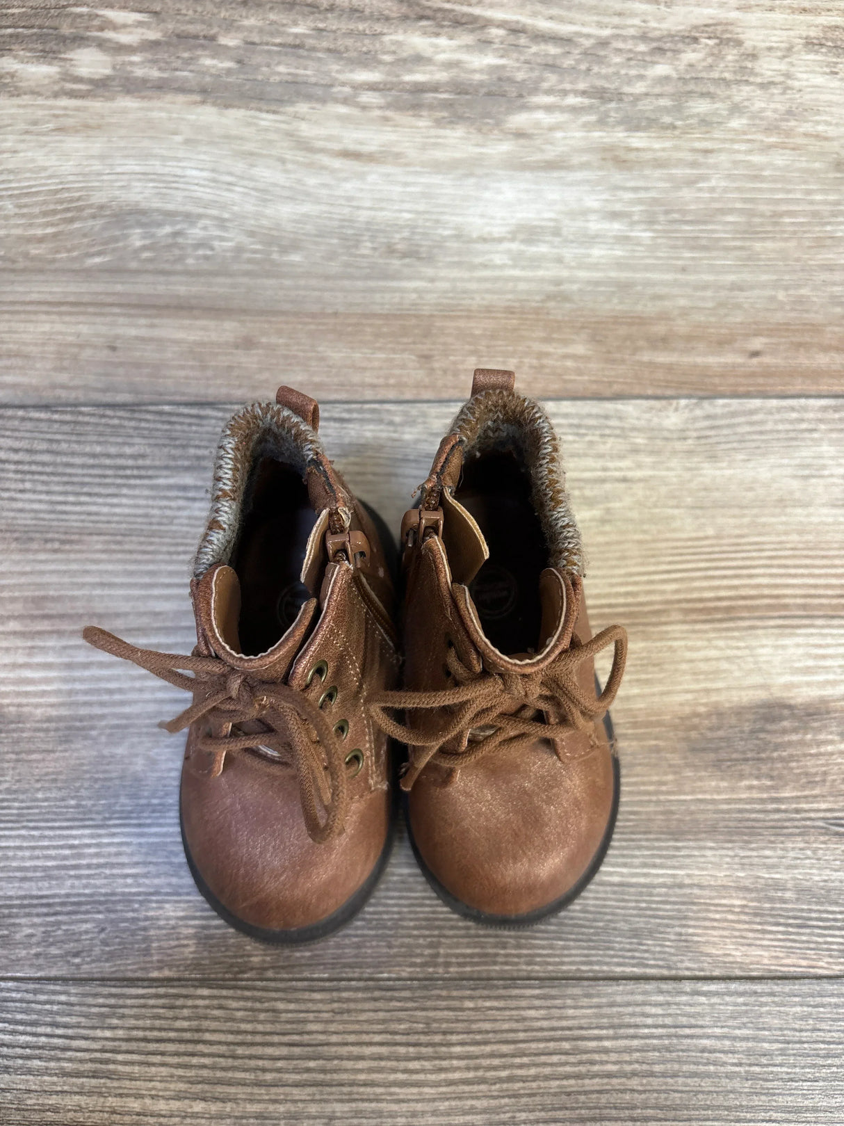 Brown toddler lace-up boots with faux fur lining on wood floor