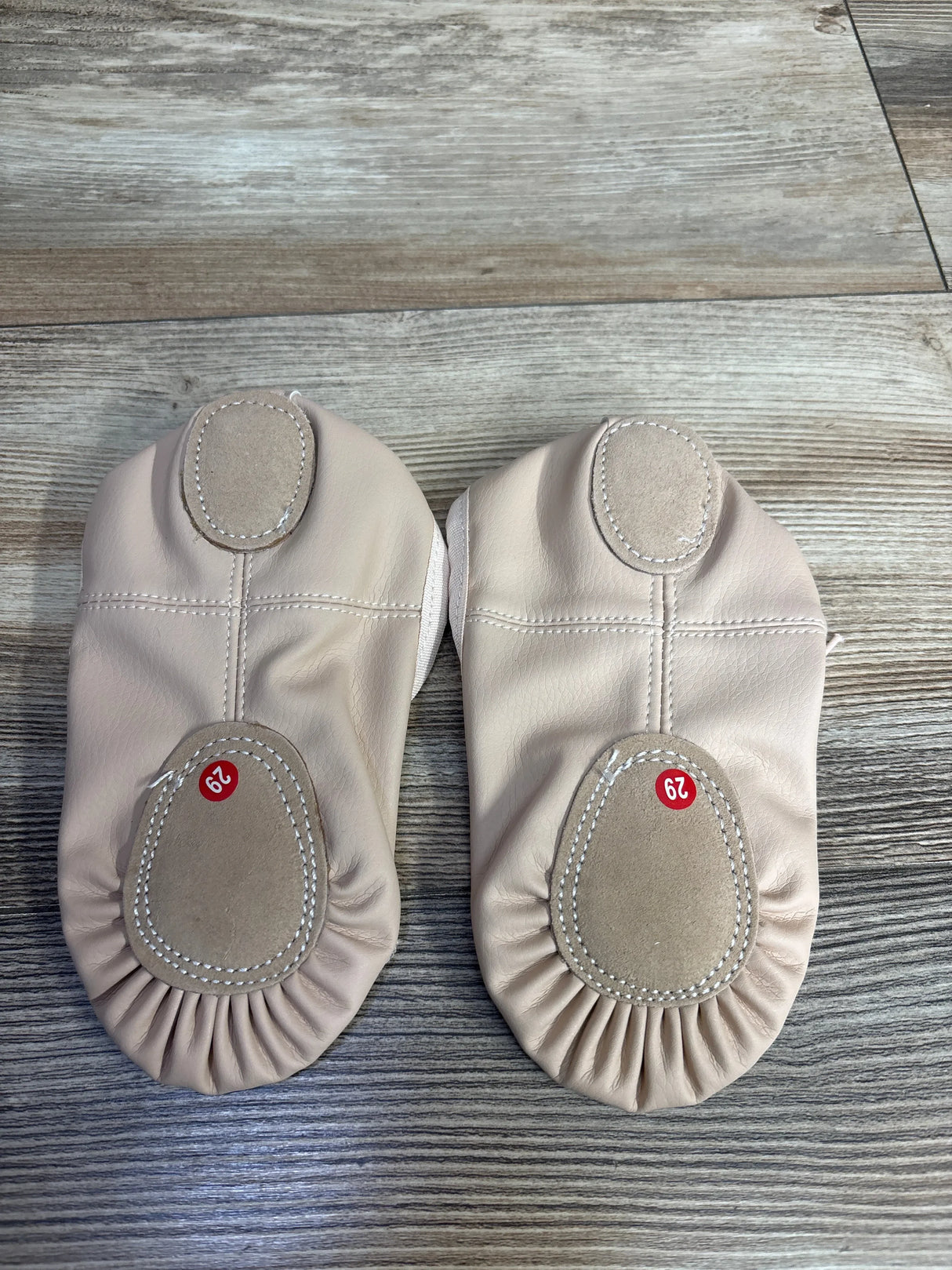 Beige leather baby shoes with suede soles, size 29, on wood floor