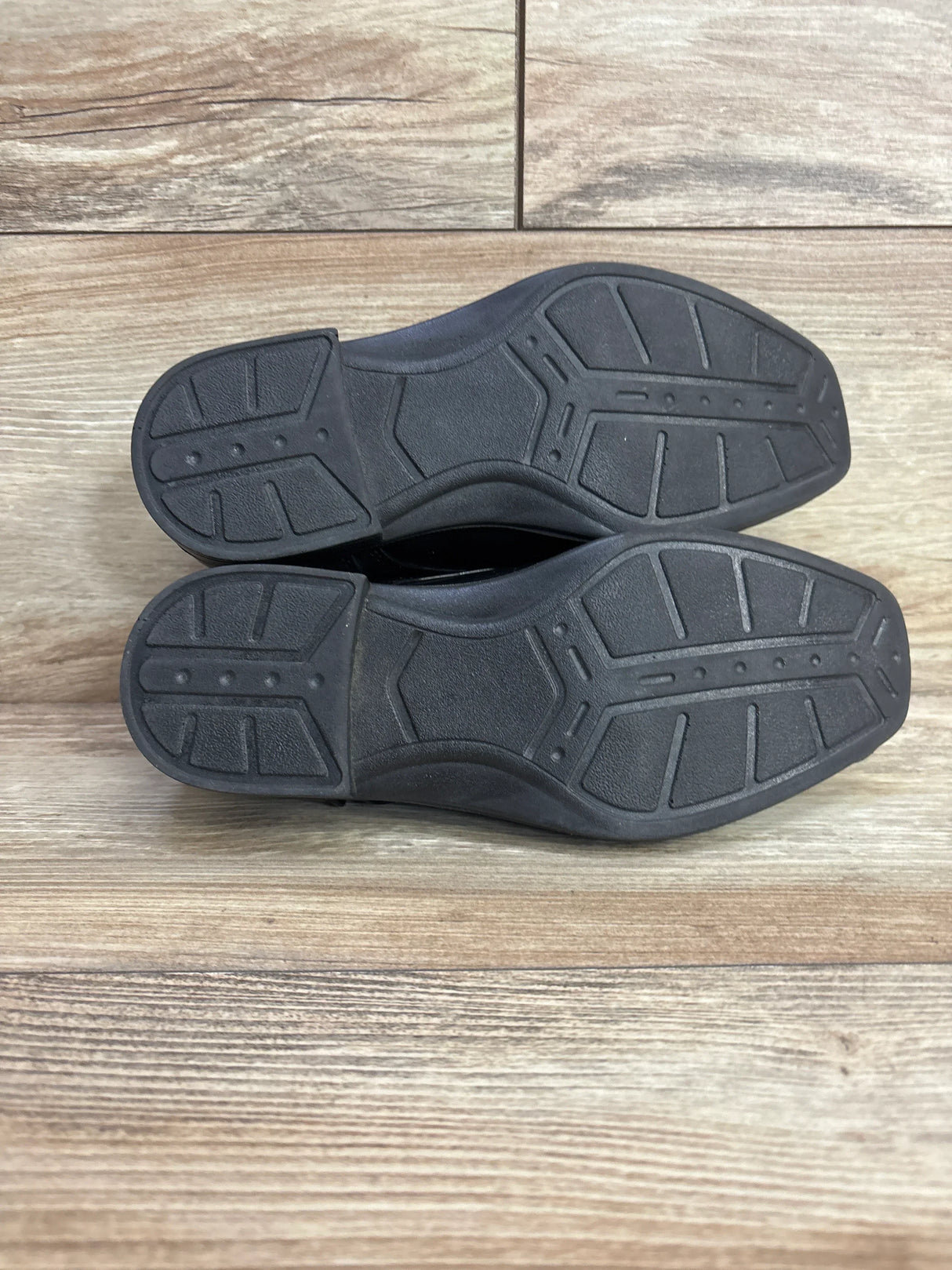 Bottom view of Deer Stags Sharp toddler dress shoes size 2Y showcasing black rubber soles with tread on wooden floor
