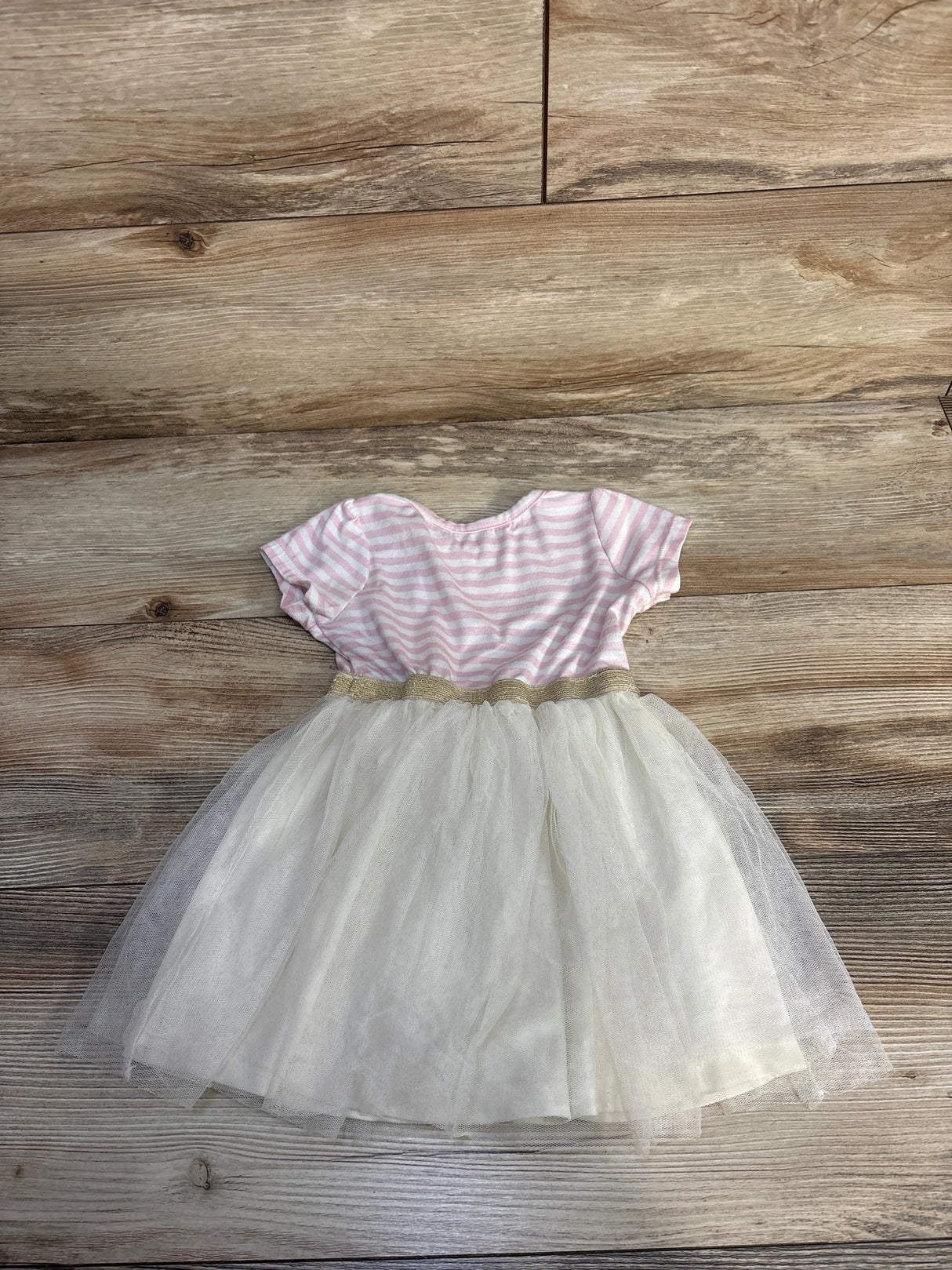 Baby girl's dress with pink and white striped top and white tulle skirt on wooden floor