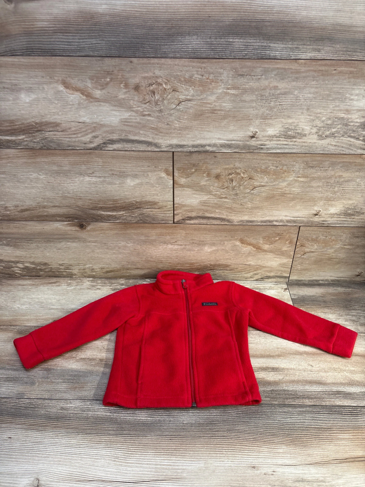Front view of Columbia red fleece full-zip toddler jacket (size 3T) showing stand collar and chest logo, laid flat on wood background