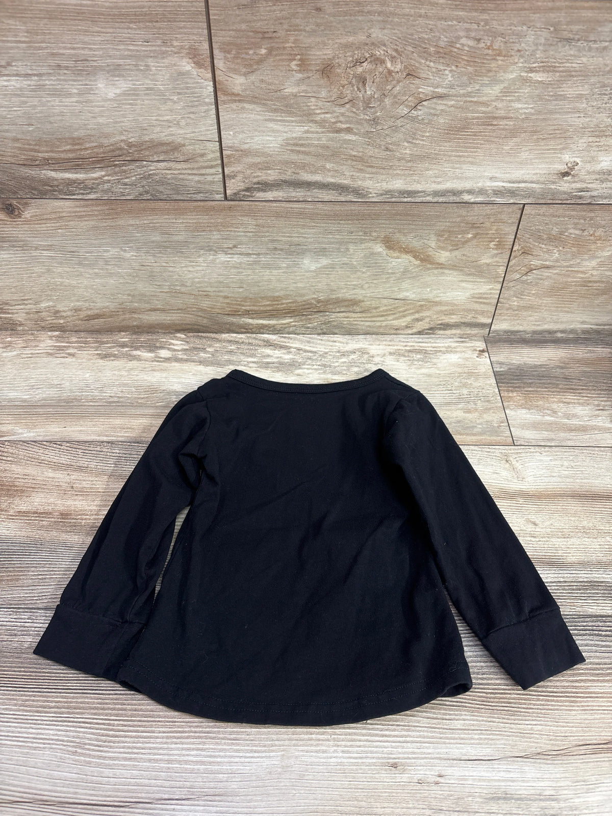 Back view of GiLiling Halloween Skeleton Shirt, black size 3 4T, with long sleeves and ribbed cuffs on wood grain flooring