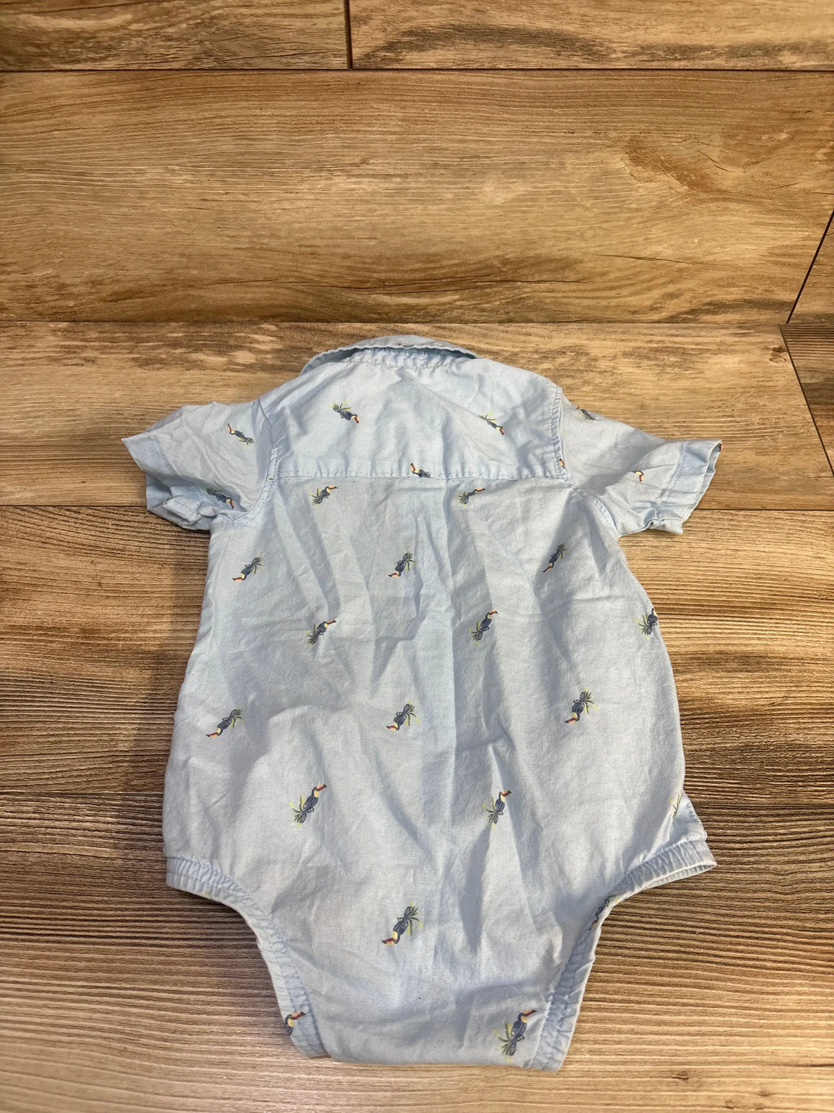 Back view of blue OshKosh bubble romper, size 12 months, with a collared neckline and short sleeves on wood grain