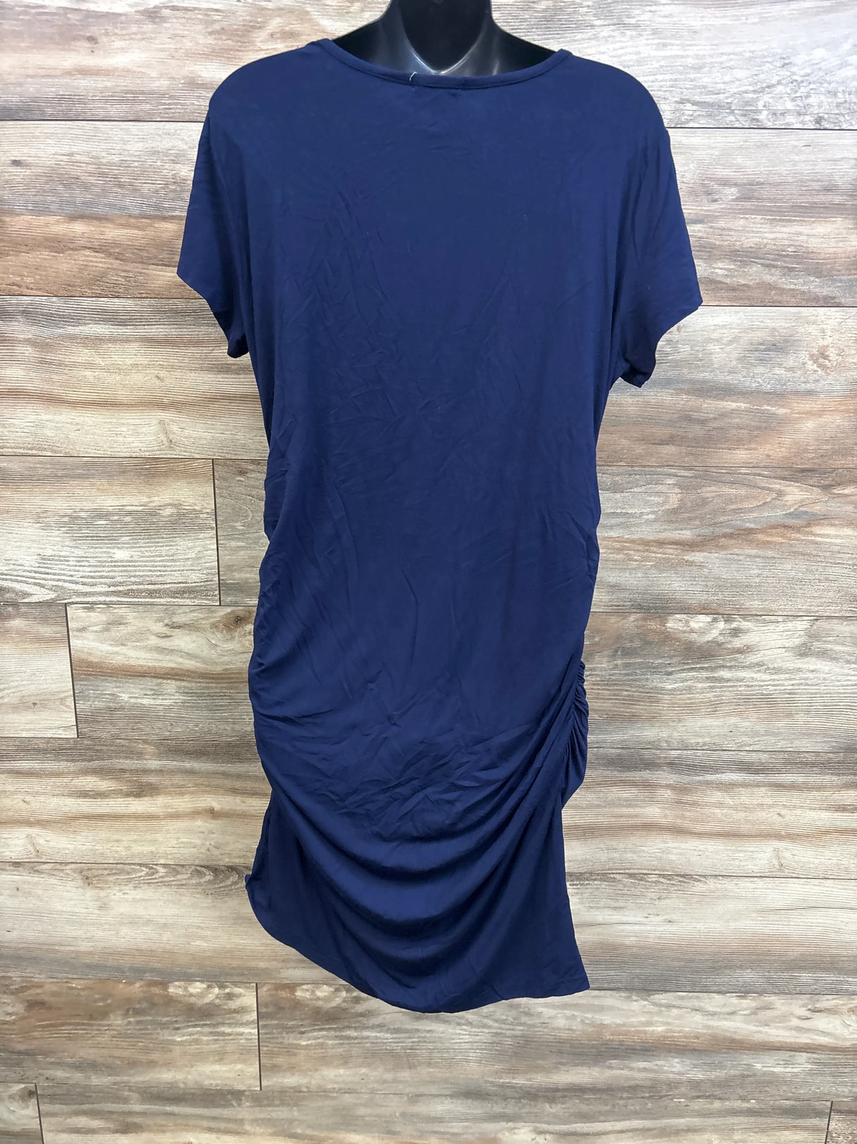 Front of navy maternity ruched bodycon dress showing side ruching and short sleeves on black mannequin with wood backdrop