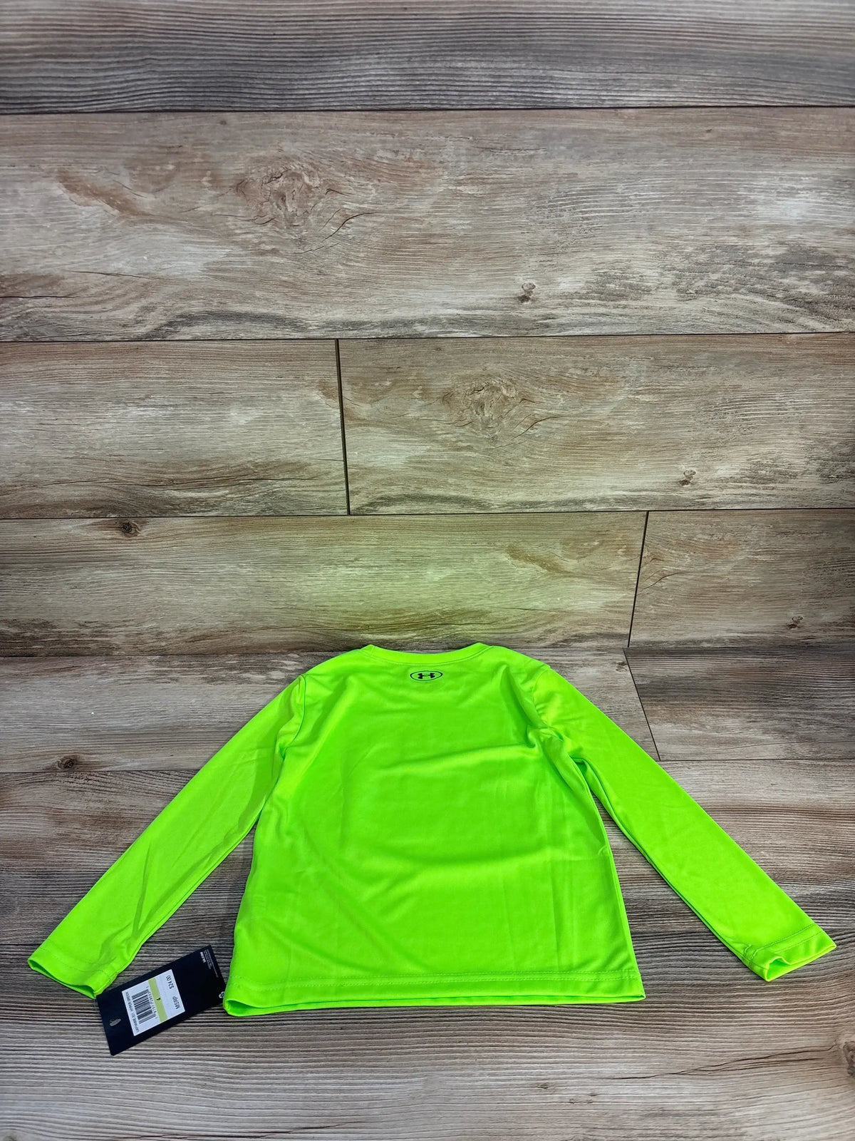 Back view of Under Armour boys' long-sleeve shirt size 4T showcasing bright hyper green color and small logo on wood background