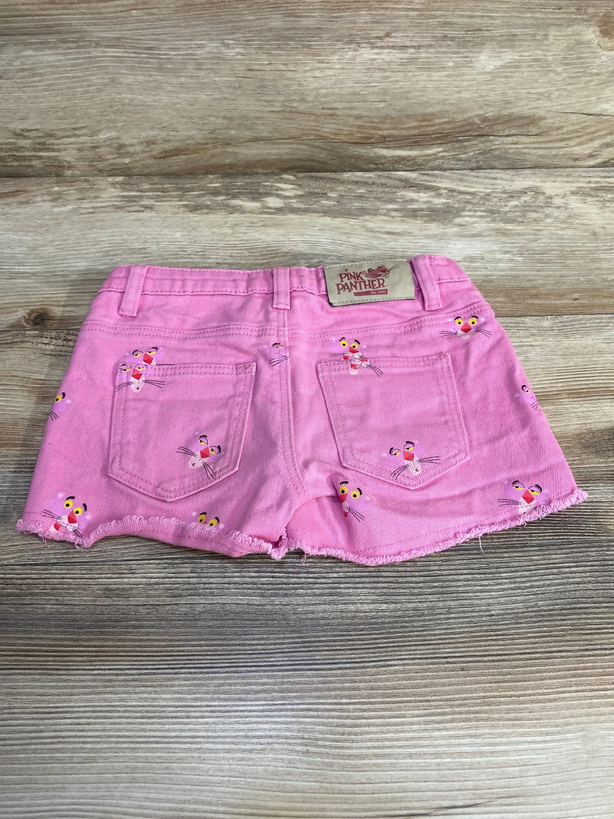 Back view of Desigual Pink Panther shorts size 5T showing Pink Panther prints frayed hem back pockets and logo patch on wood