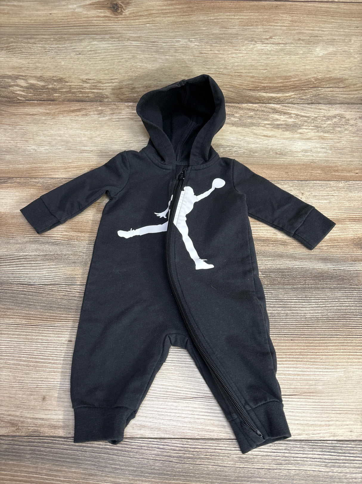 Black hooded baby onesie with white basketball player graphic and zipper front on wooden floor