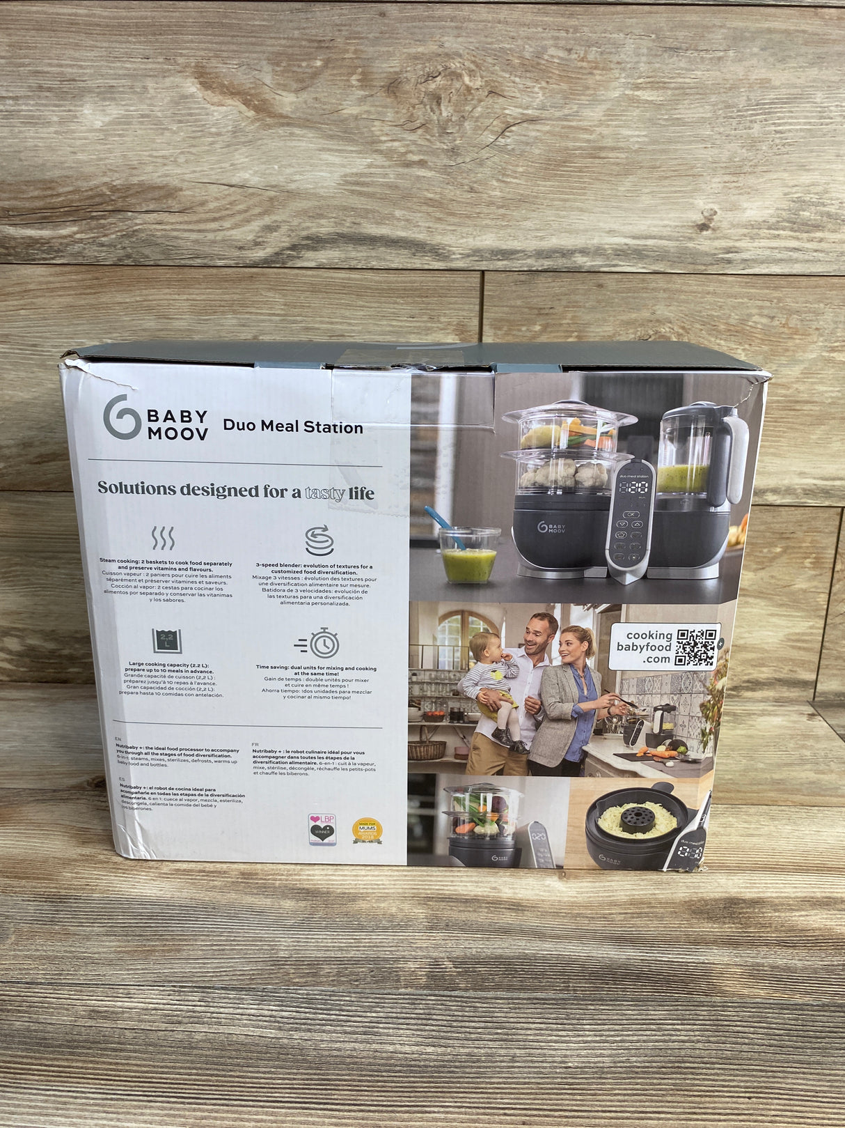 Babymoov Duo Meal Station baby food maker box on wood background, showing product and family photo