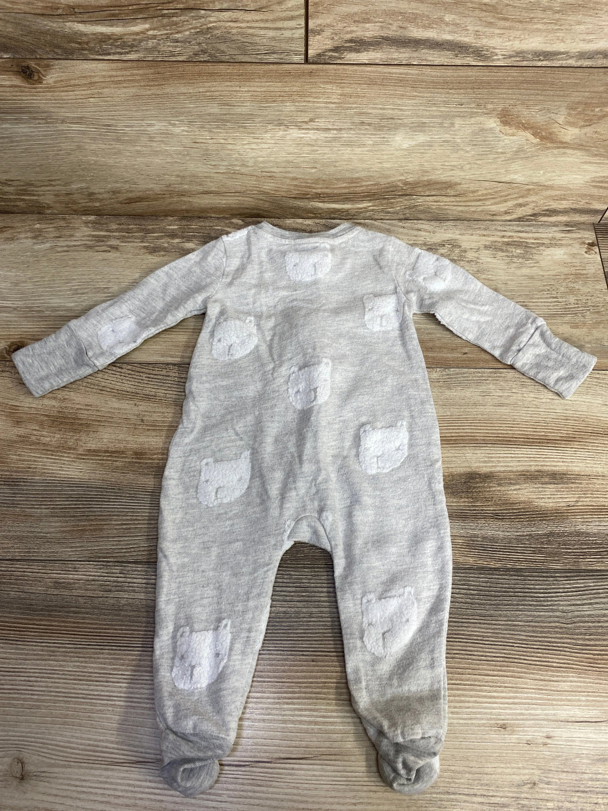 Gray baby onesie with white bear face patches laid flat on wood surface