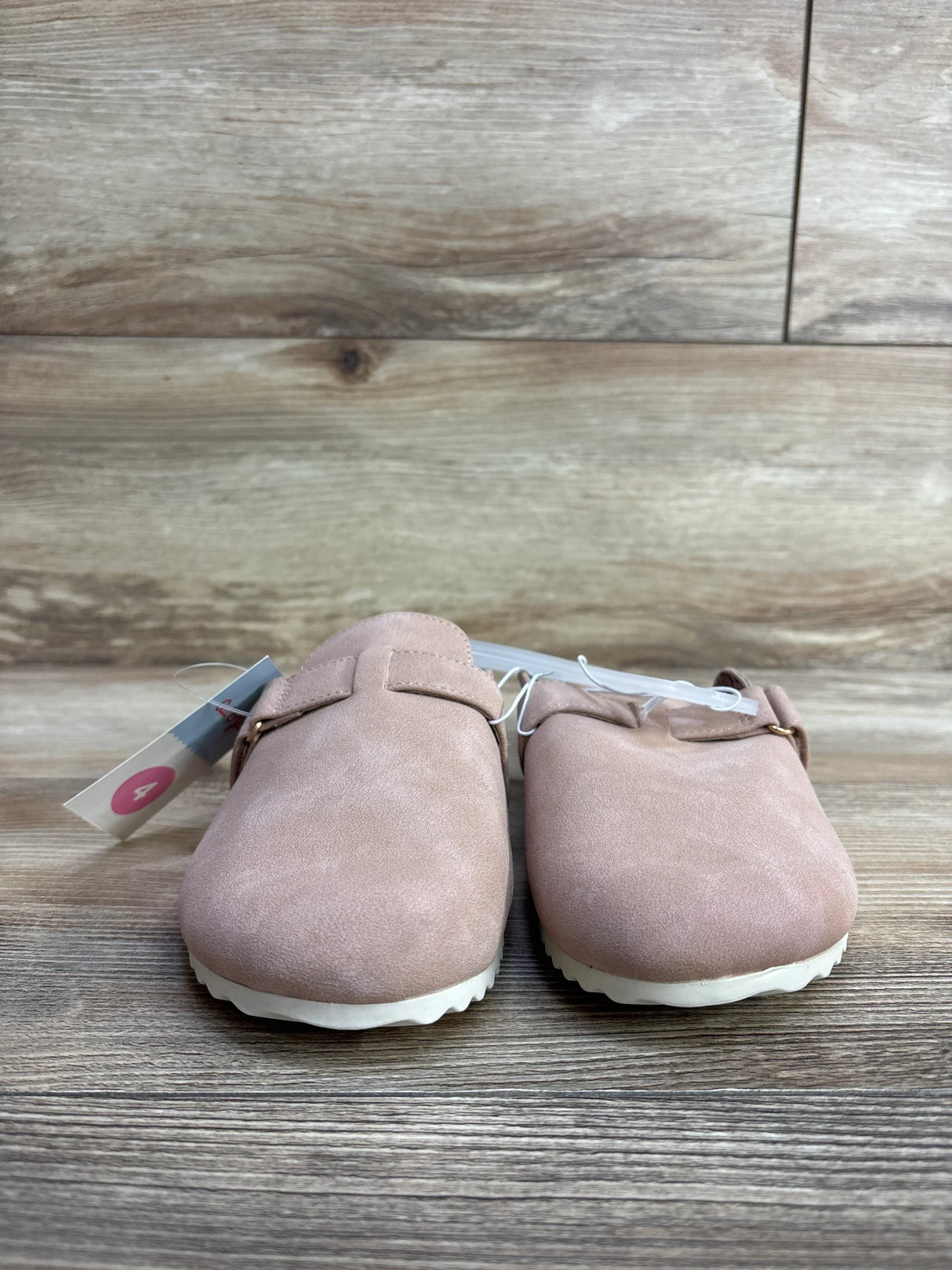 Pink suede toddler slip-on shoes with white soles on wood background