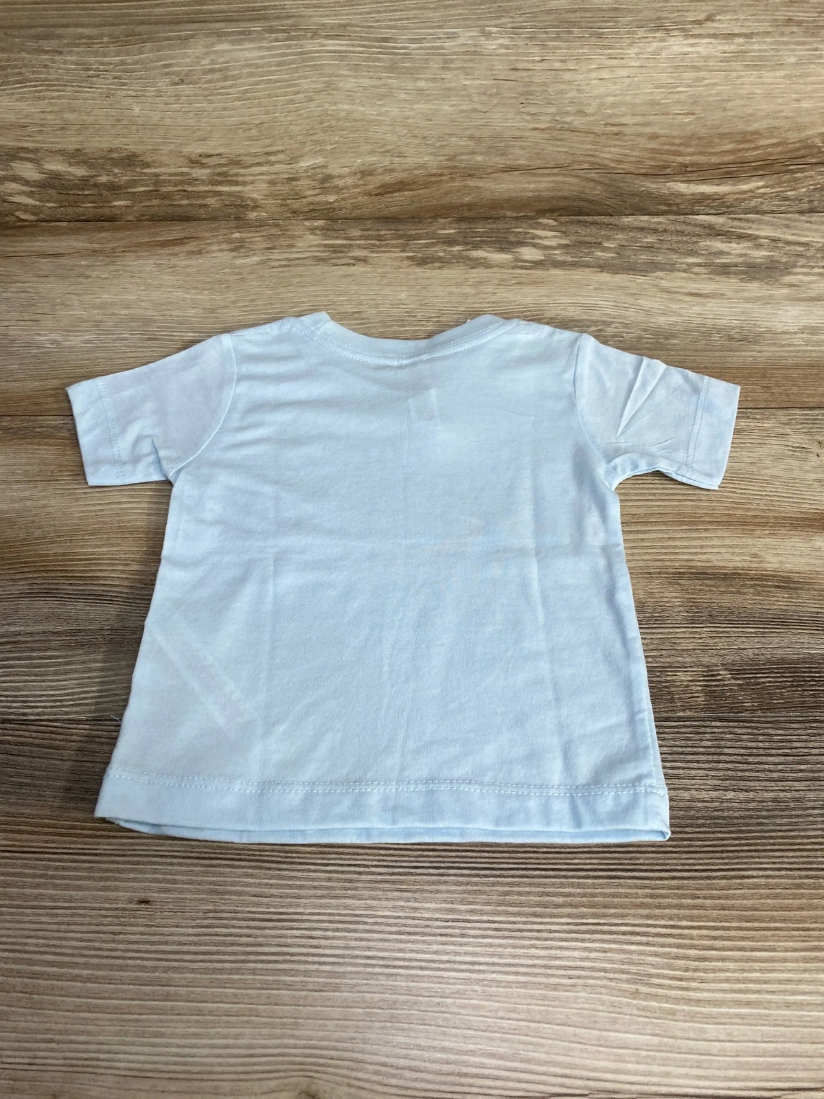 Back view of Bella Canvas blue baby t-shirt size 6-12 months showing short sleeves and crew neck on wood background