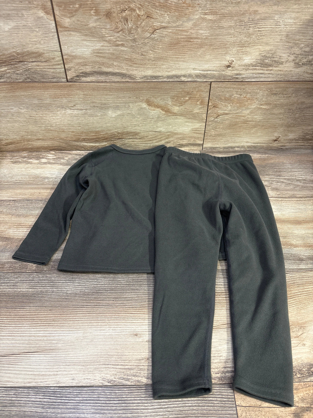 Flat lay of gray two-piece pajama set in size 4T showing long-sleeve top and pants on wood flooring