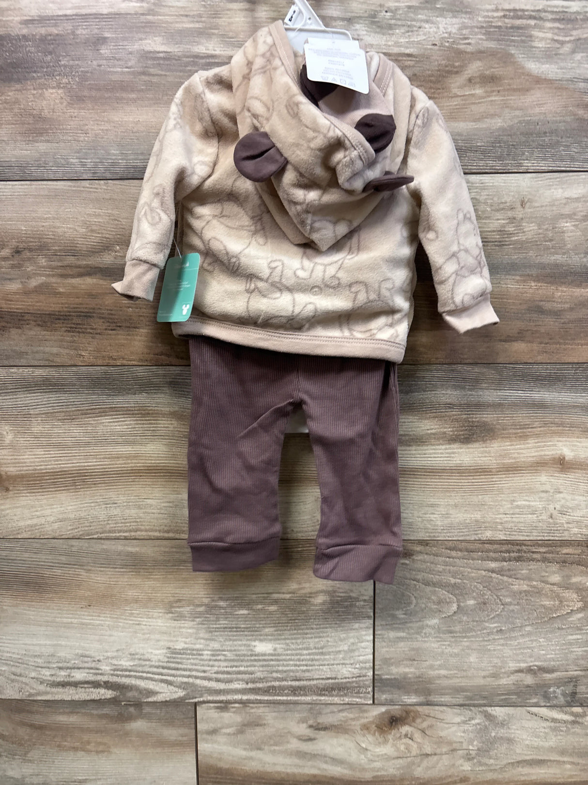 Front of Winnie the Pooh baby jacket set with hood ears and fleece print, brown ribbed pants on wood background