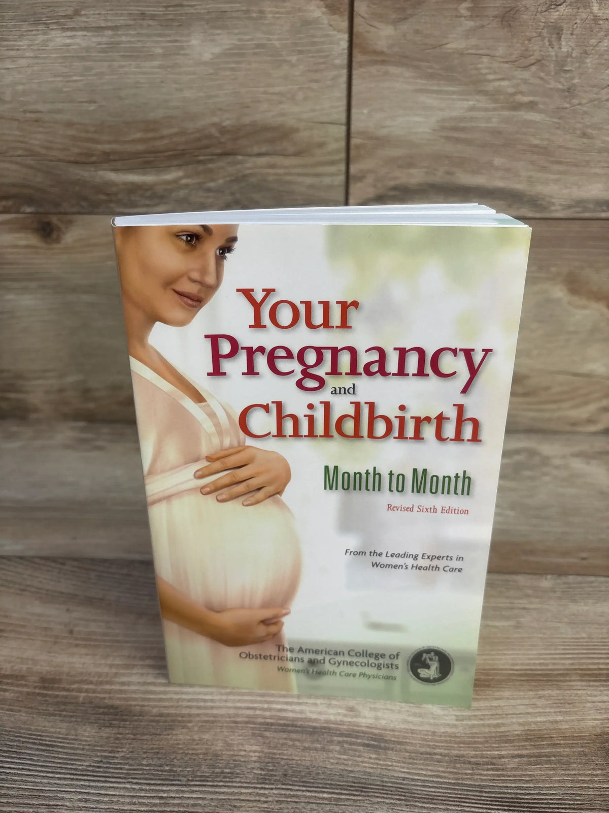 Front cover of Your Pregnancy and Childbirth: Month to Month, Sixth Edition paperback book with pregnant woman on wood