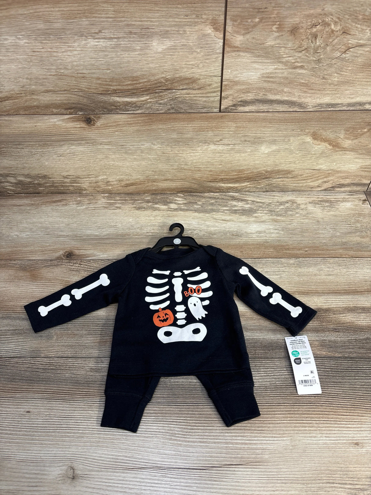 Black baby Halloween skeleton onesie with pumpkin and ghost, newborn size, on hanger