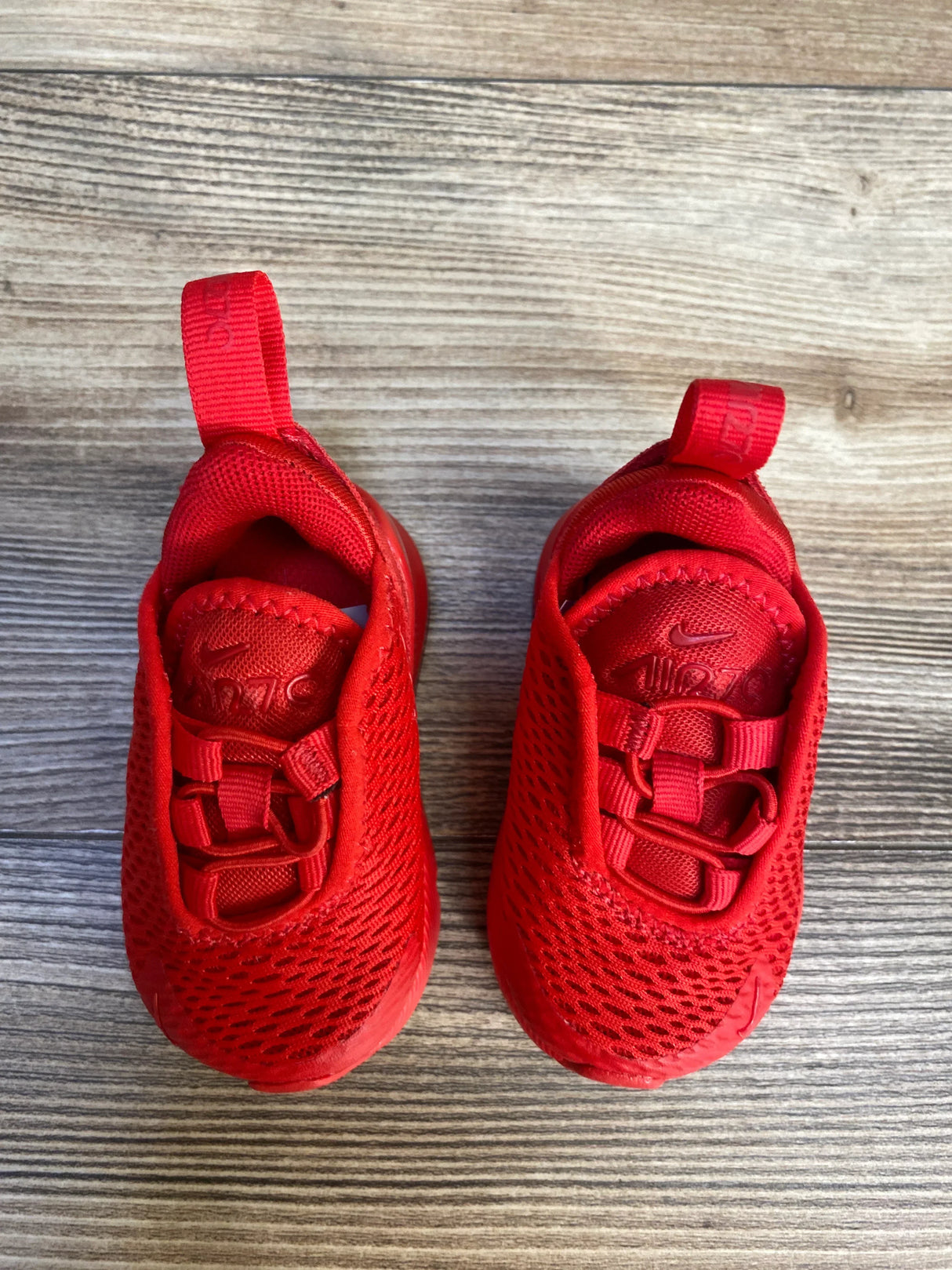 Red toddler sneakers with mesh design on wood background, gently used kids shoes
