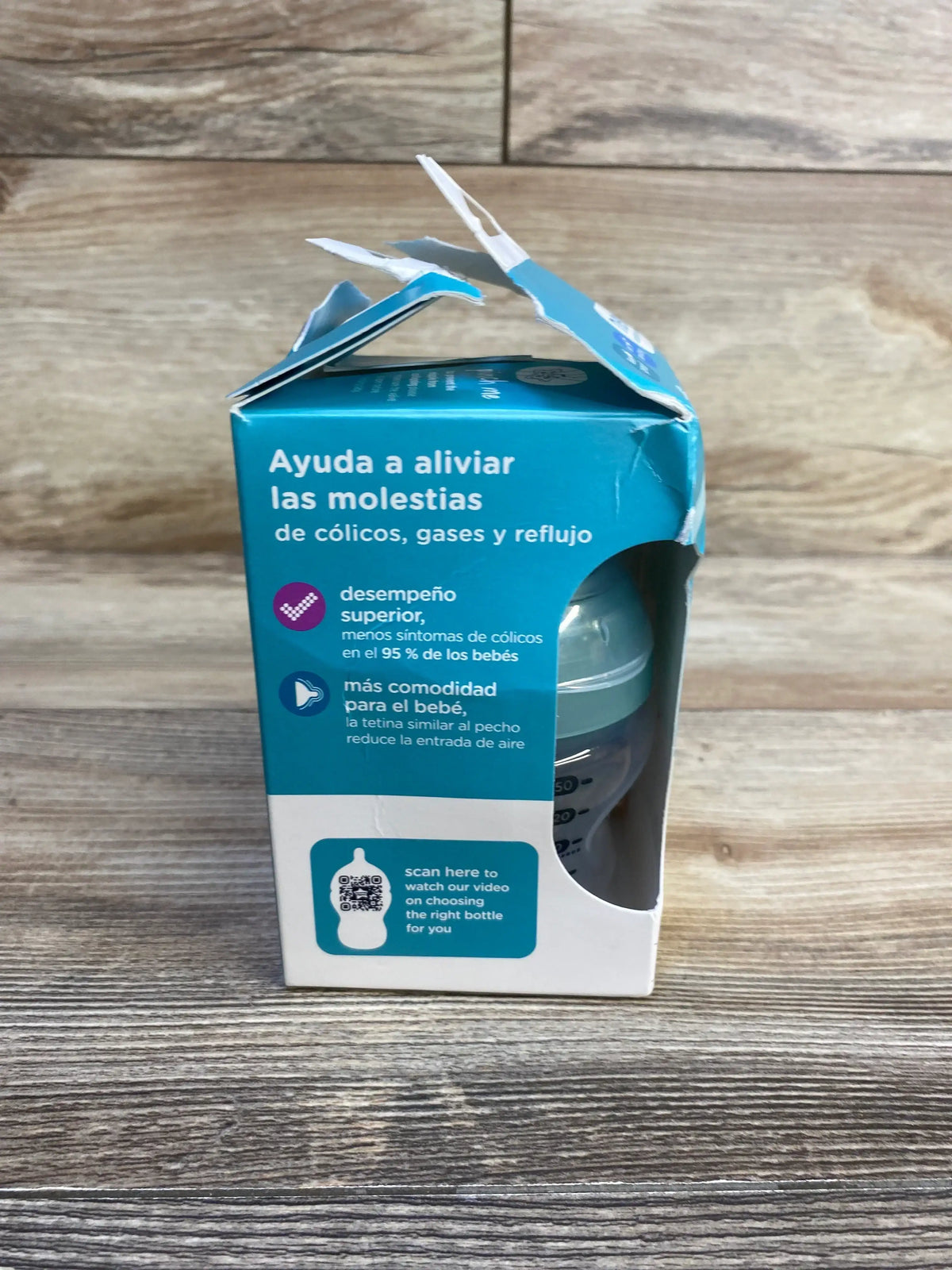 Front view of Tommee Tippee Advanced Anti Colic 5oz bottle in opened blue box showing Spanish headline about colic on wood