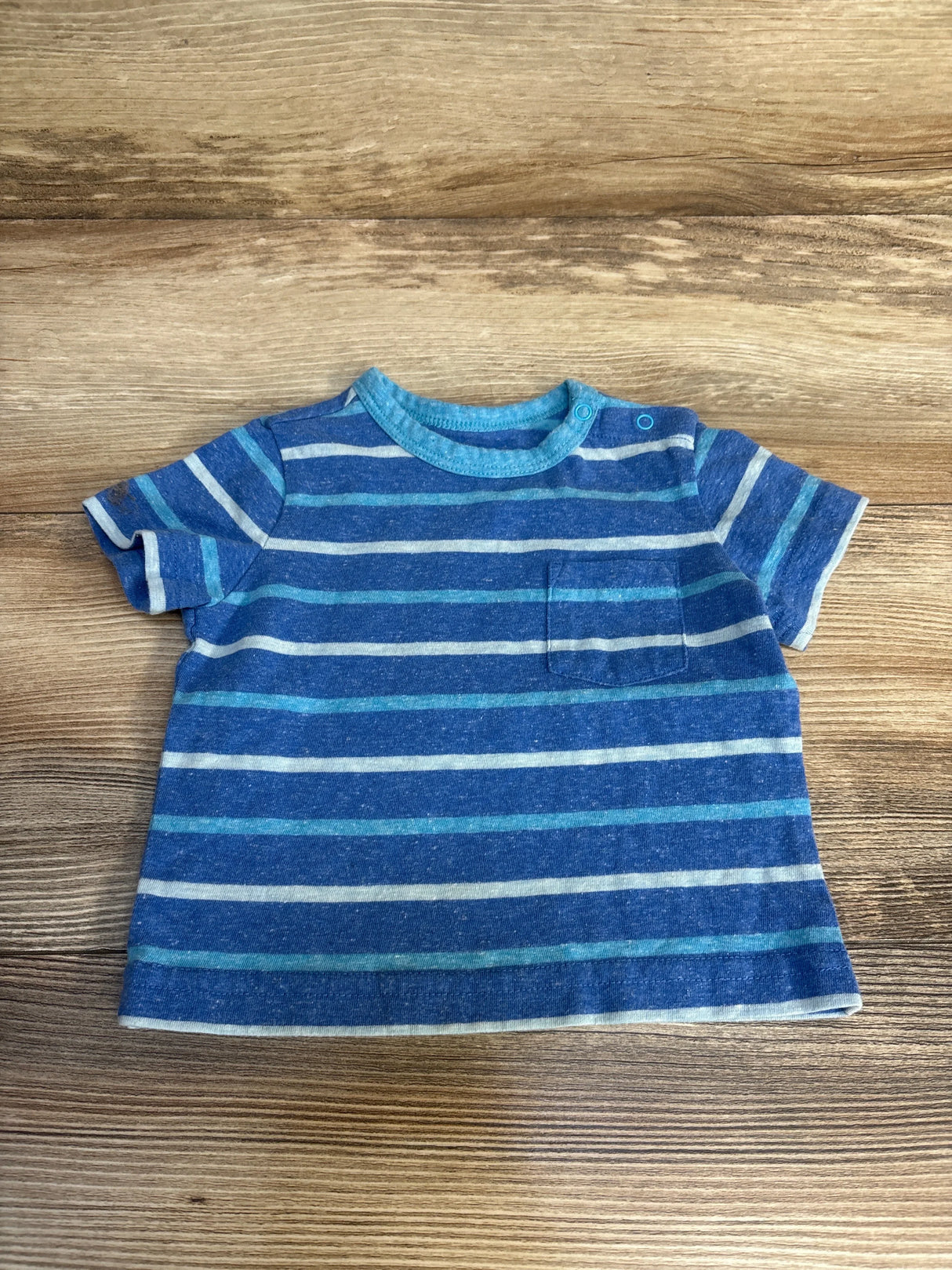 Blue striped short sleeve toddler shirt with chest pocket on wood background