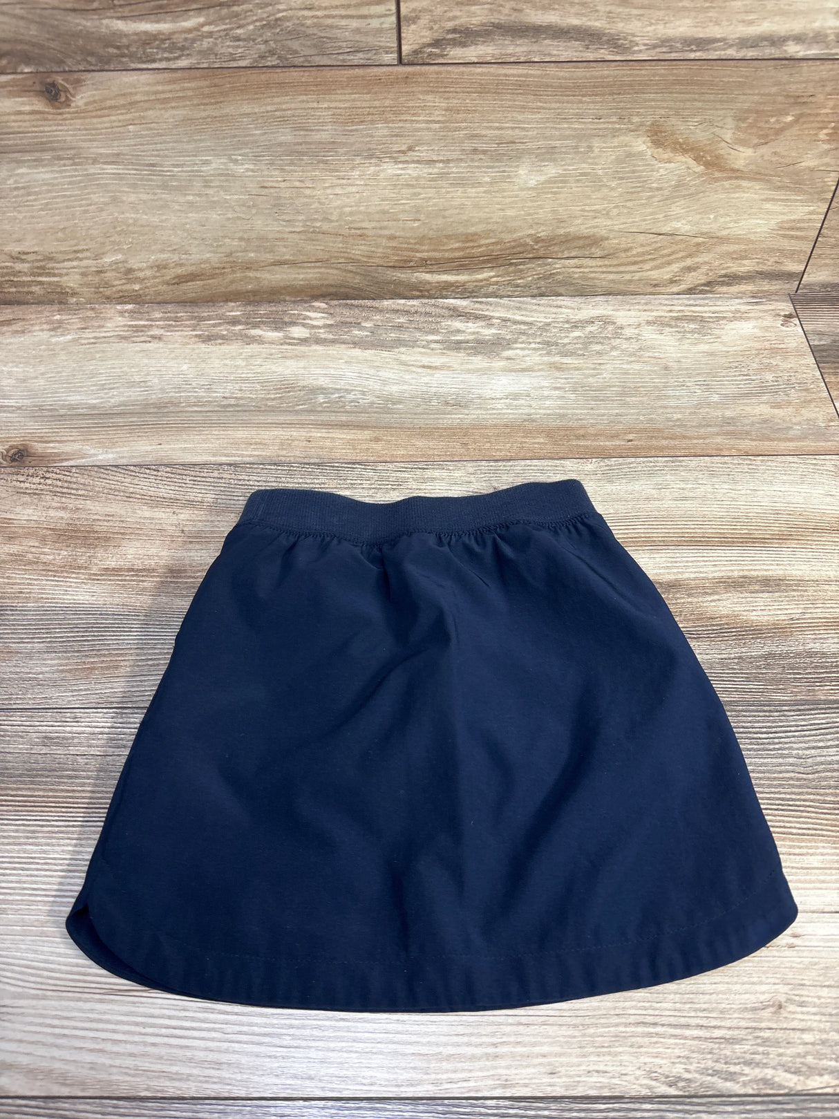 Flat-lay of navy Cat and Jack quick-dry school skort toddler 4T showing elastic waistband on wood background