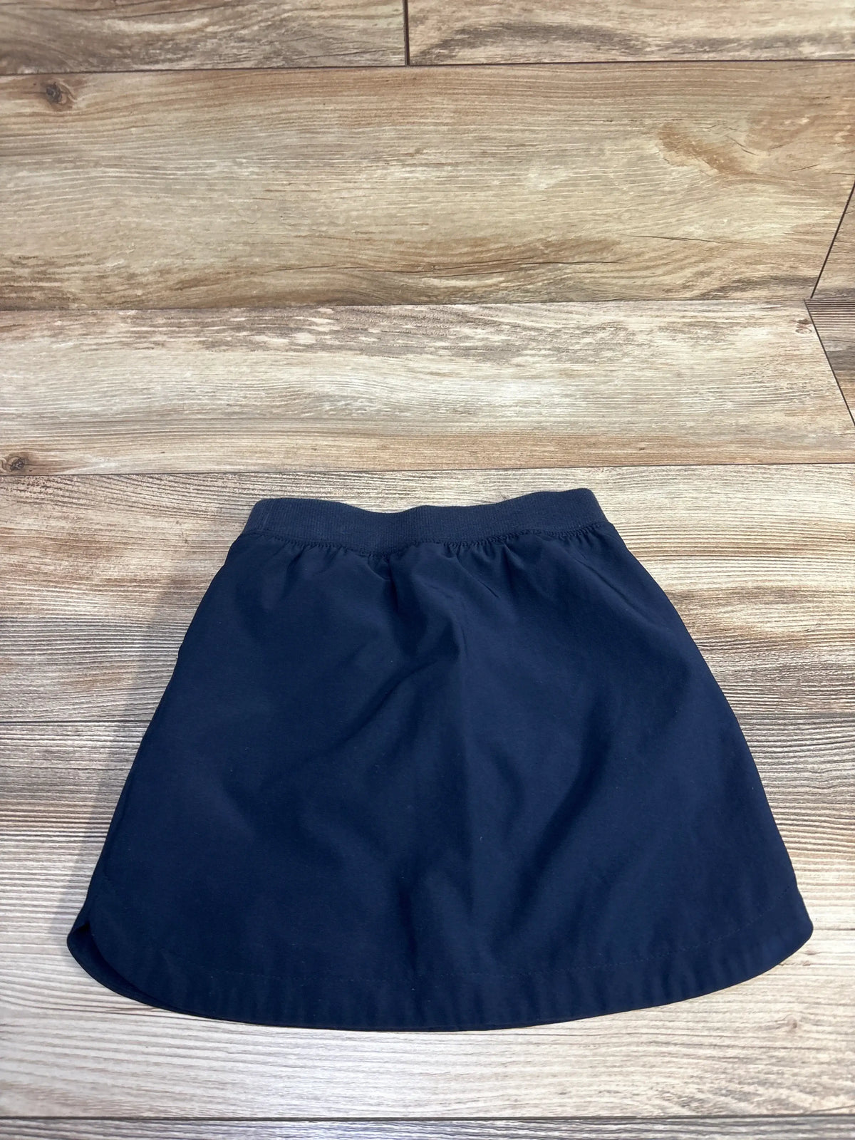 Flat-lay of navy Cat and Jack quick-dry school skort toddler 4T showing elastic waistband on wood background