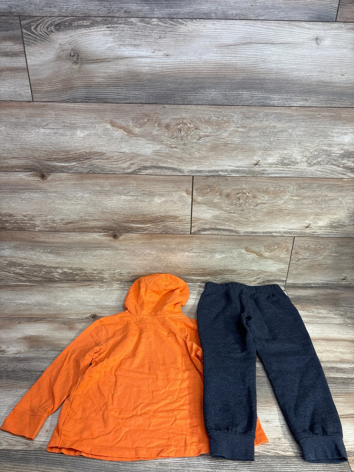 Orange kids hoodie and navy joggers set on wood floor, children's clothing resale