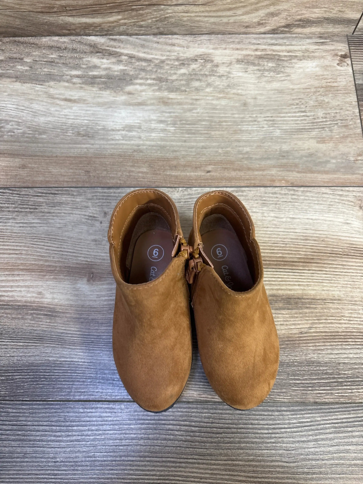 Top view of Cat & Jack Penelope boots in brown, showcasing side zippers with a wood-grain background