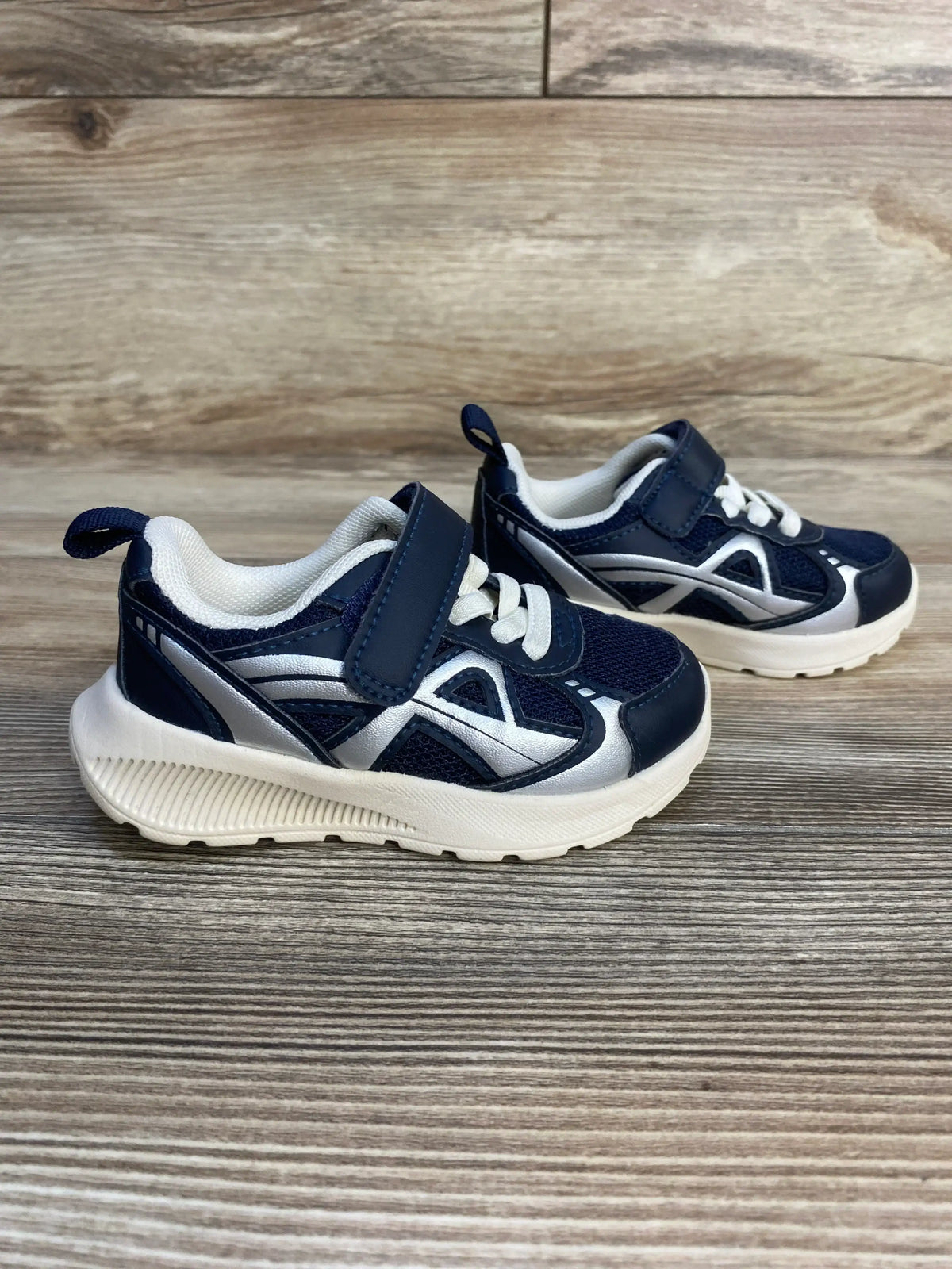 Navy blue and white toddler athletic sneakers with velcro strap on wood background