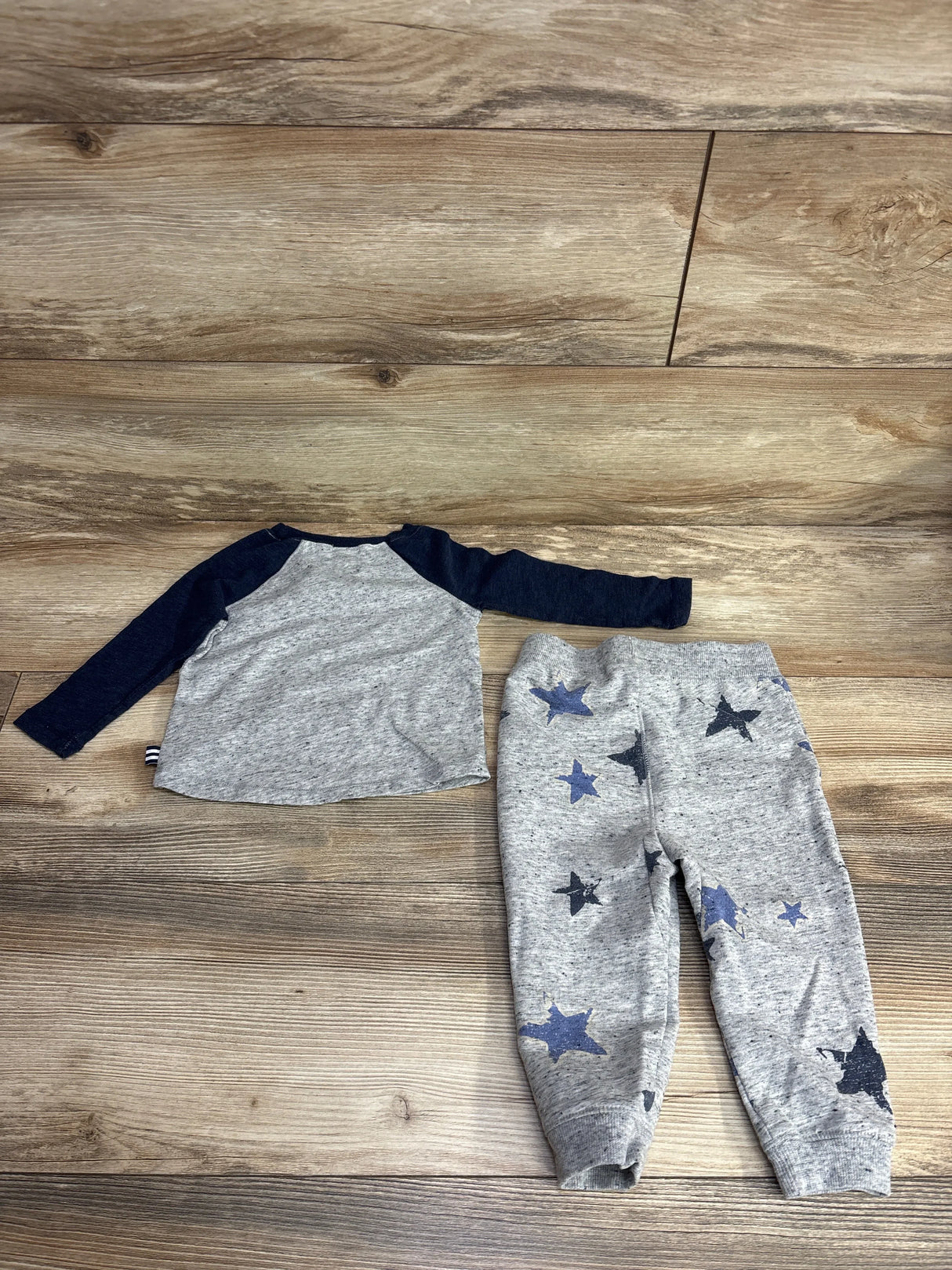 Gray and navy long sleeve toddler shirt with matching star print pants on wood floor