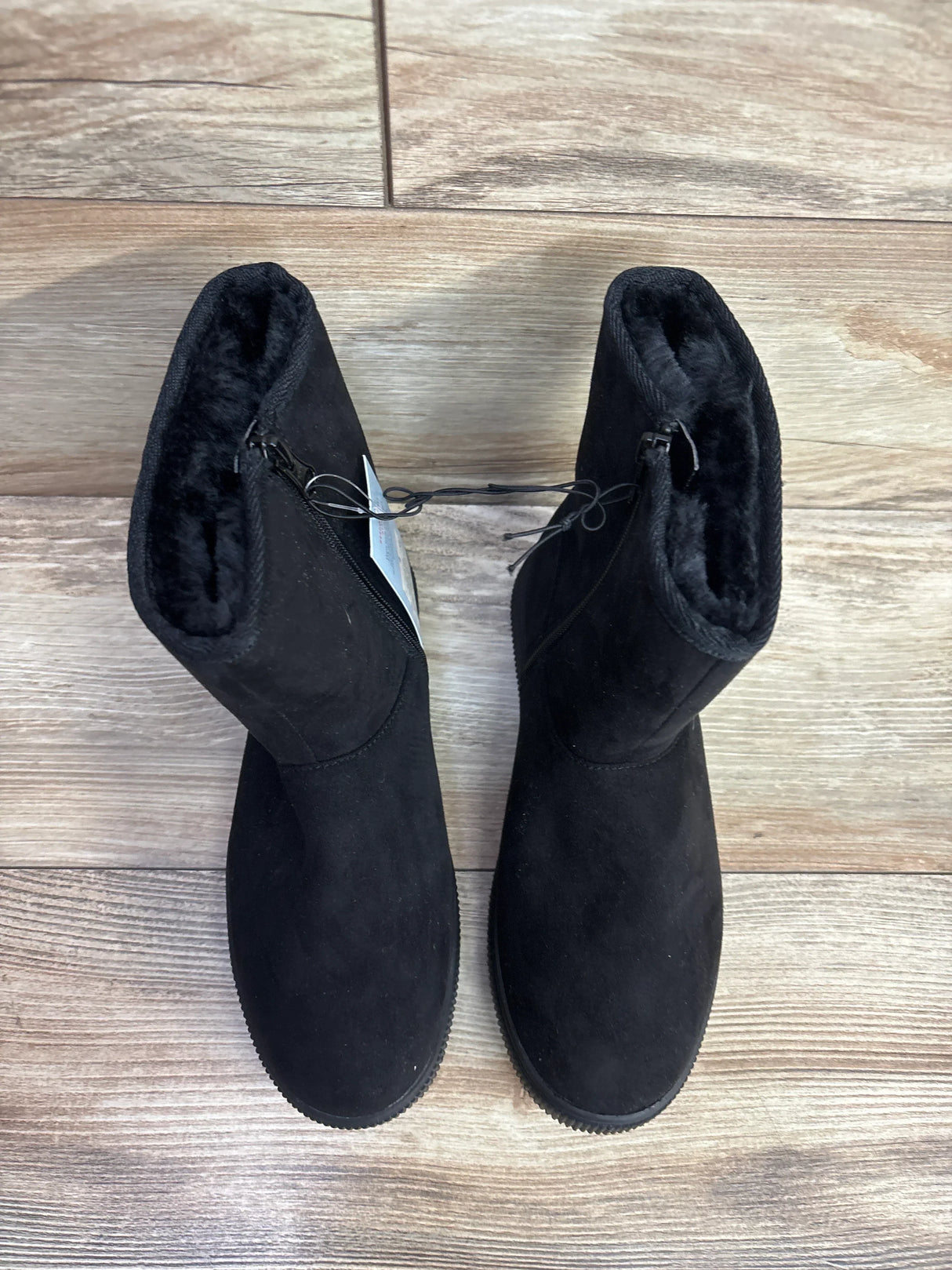 Pair of black children's winter boots with fur lining on wooden floor at a kids resale store
